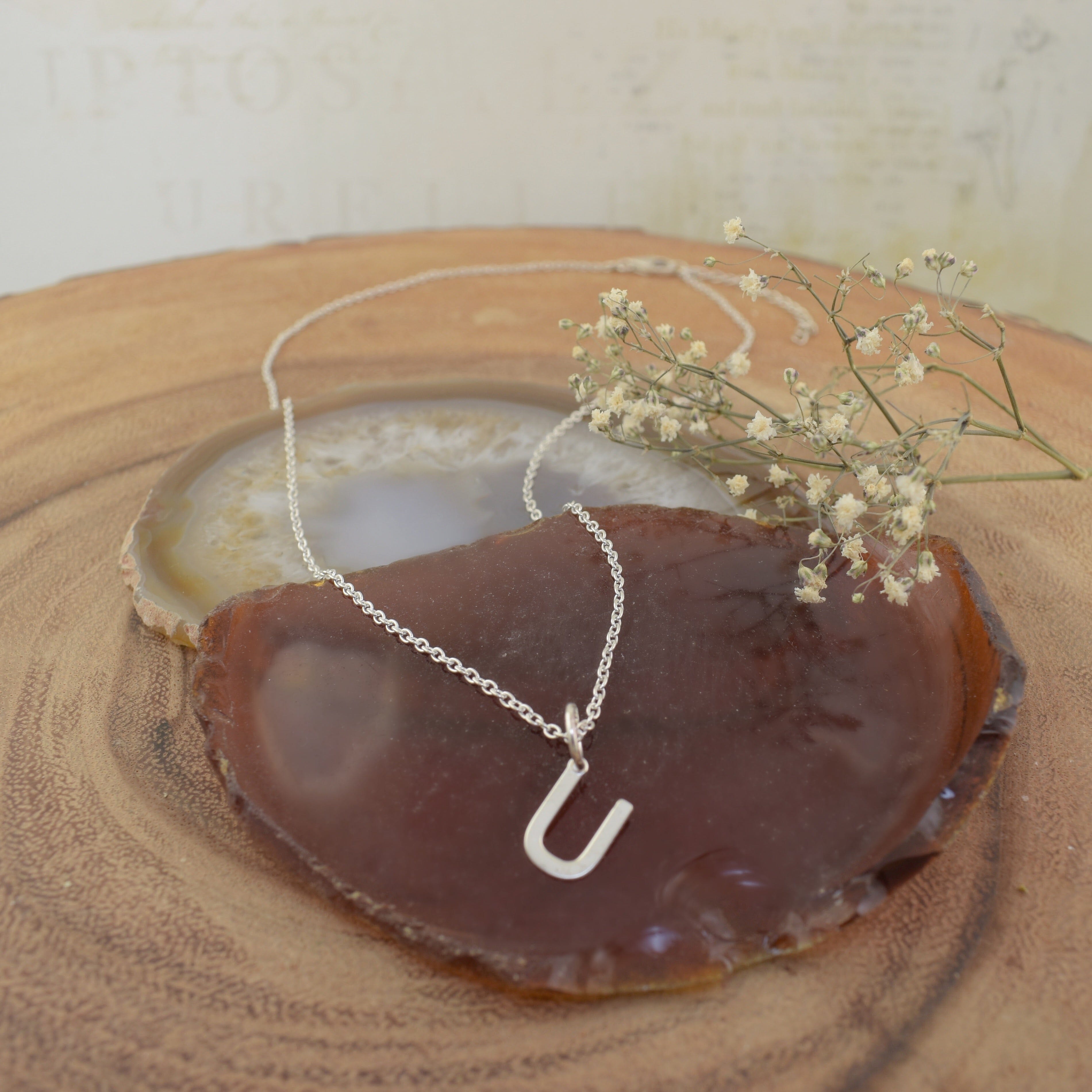 A sterling silver necklace featuring a high polished U pendant