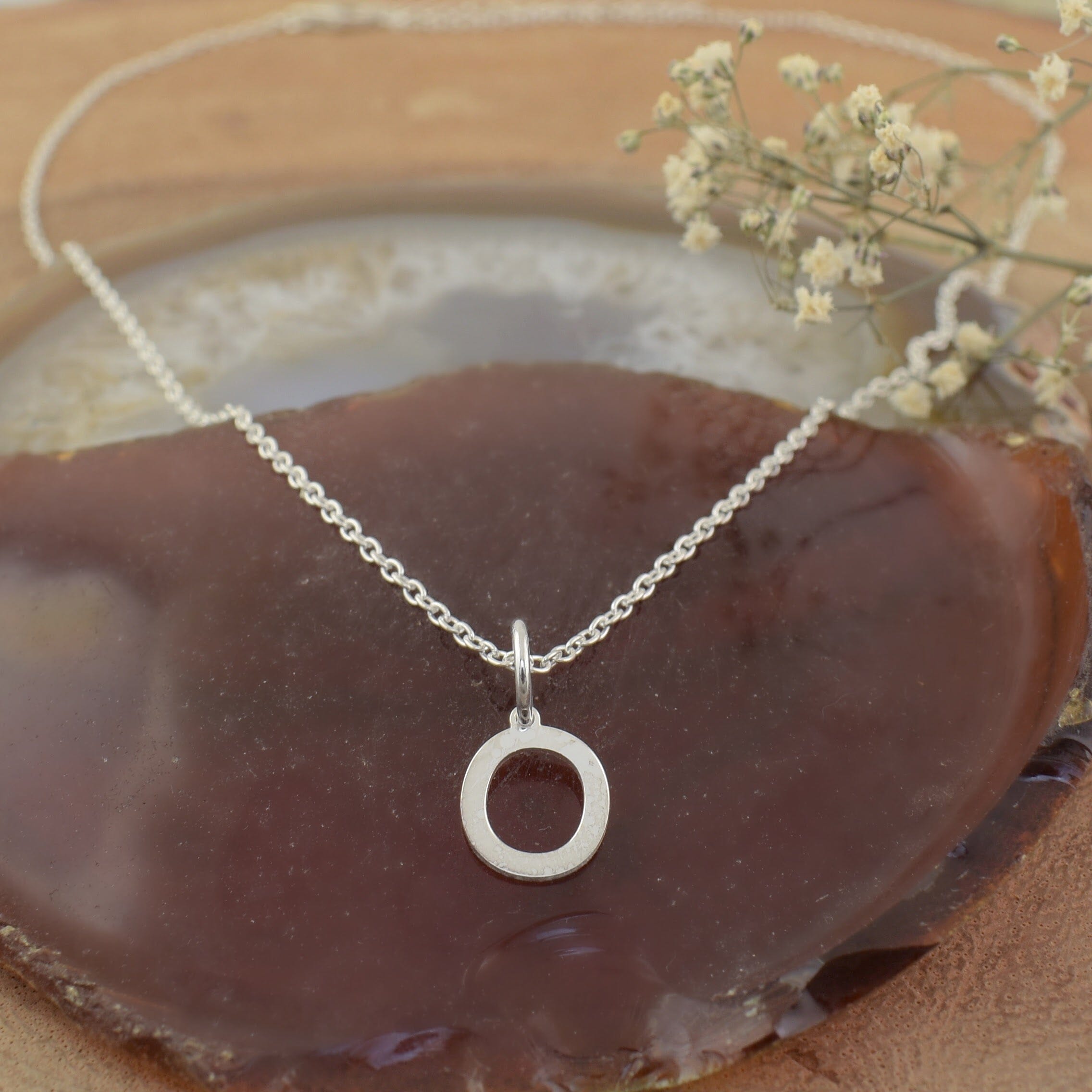 A sterling silver necklace featuring an initial pendant "O"