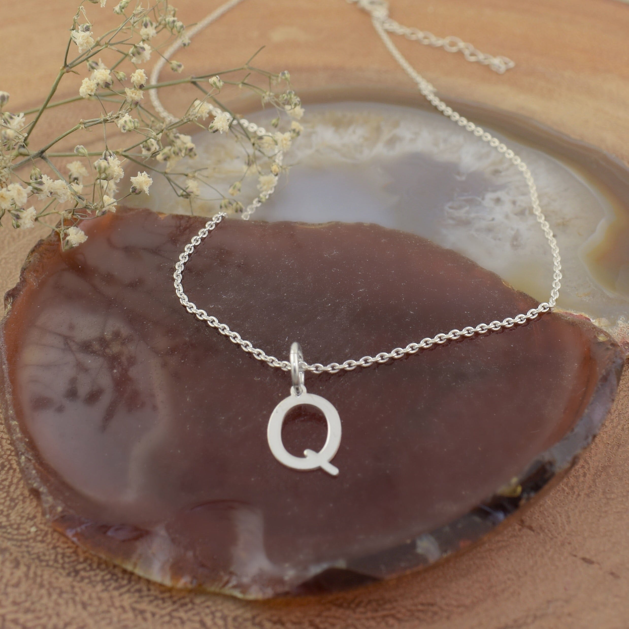 A sterling silver necklace featuring an initial pendant "Q"