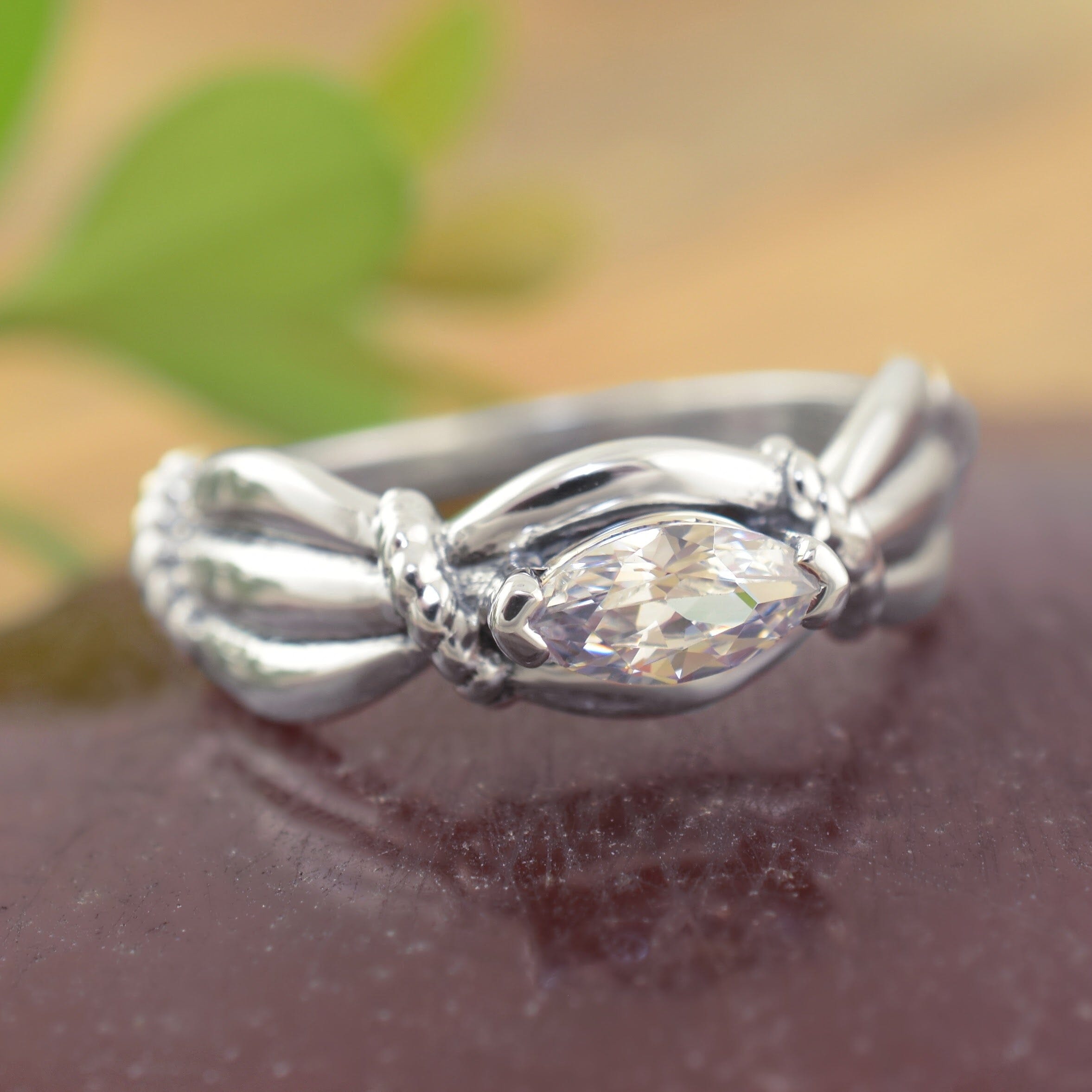 a sterling silver ring with a twisted band and a marquise-cut clear gemstone
