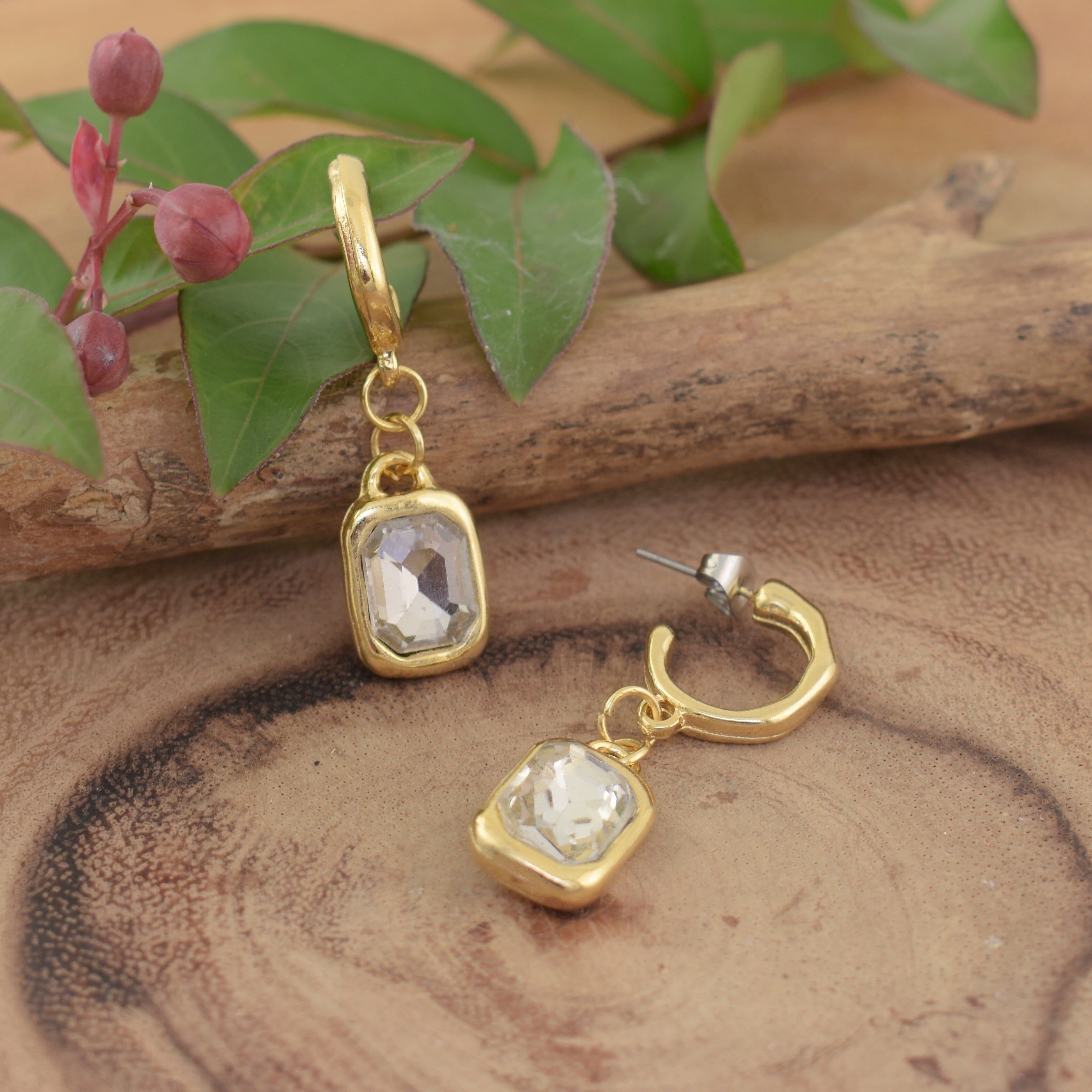 a pair of posh boutique earrings that feature a clear rectangular gemstone in a gold setting