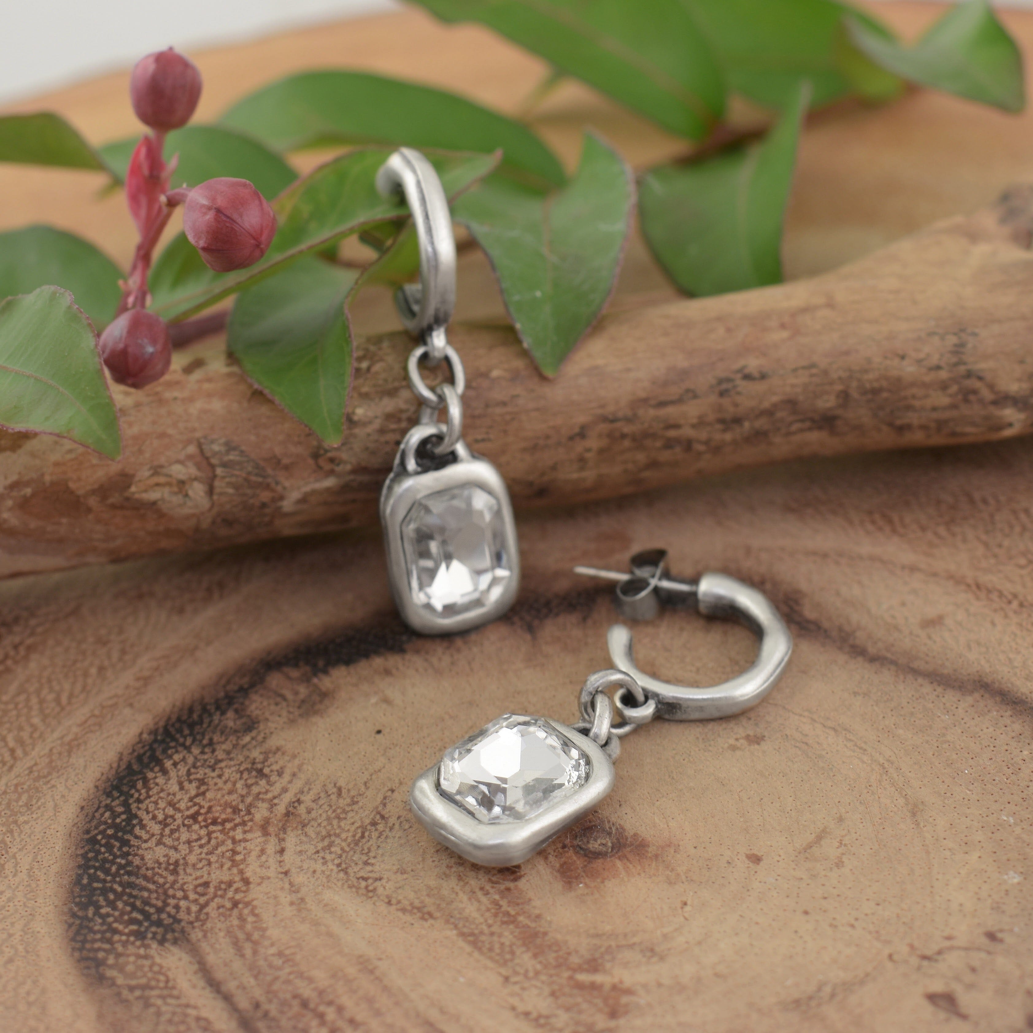 a pair of posh boutique earrings that feature a clear rectangular gemstone in a silver setting