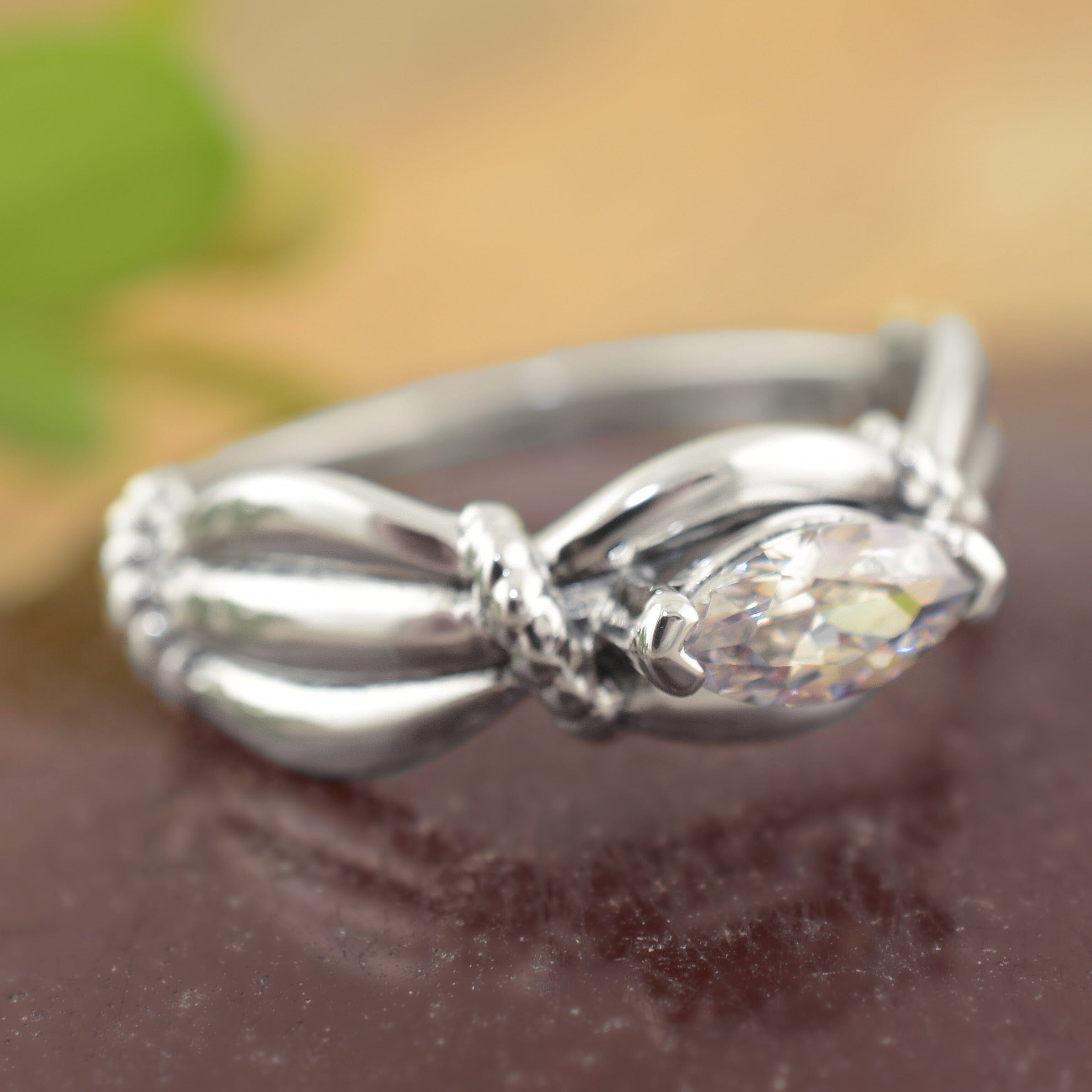 a sterling silver ring with a marquise-cut clear gemstone, featuring a textured twisted knot design on the band