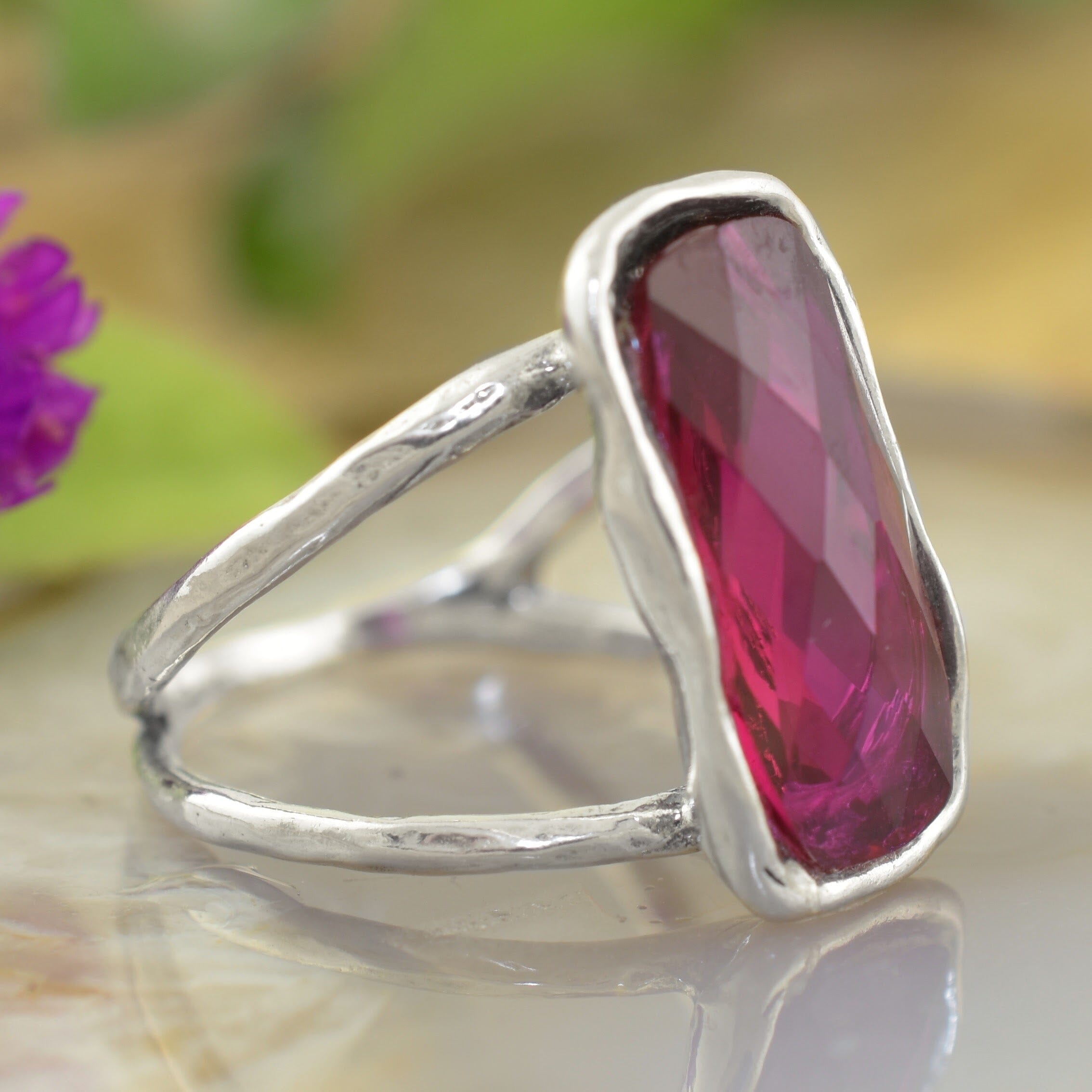 a sterling silver ring featuring a large, faceted rectangular magenta-pink gemstone sitting on an organic silver band