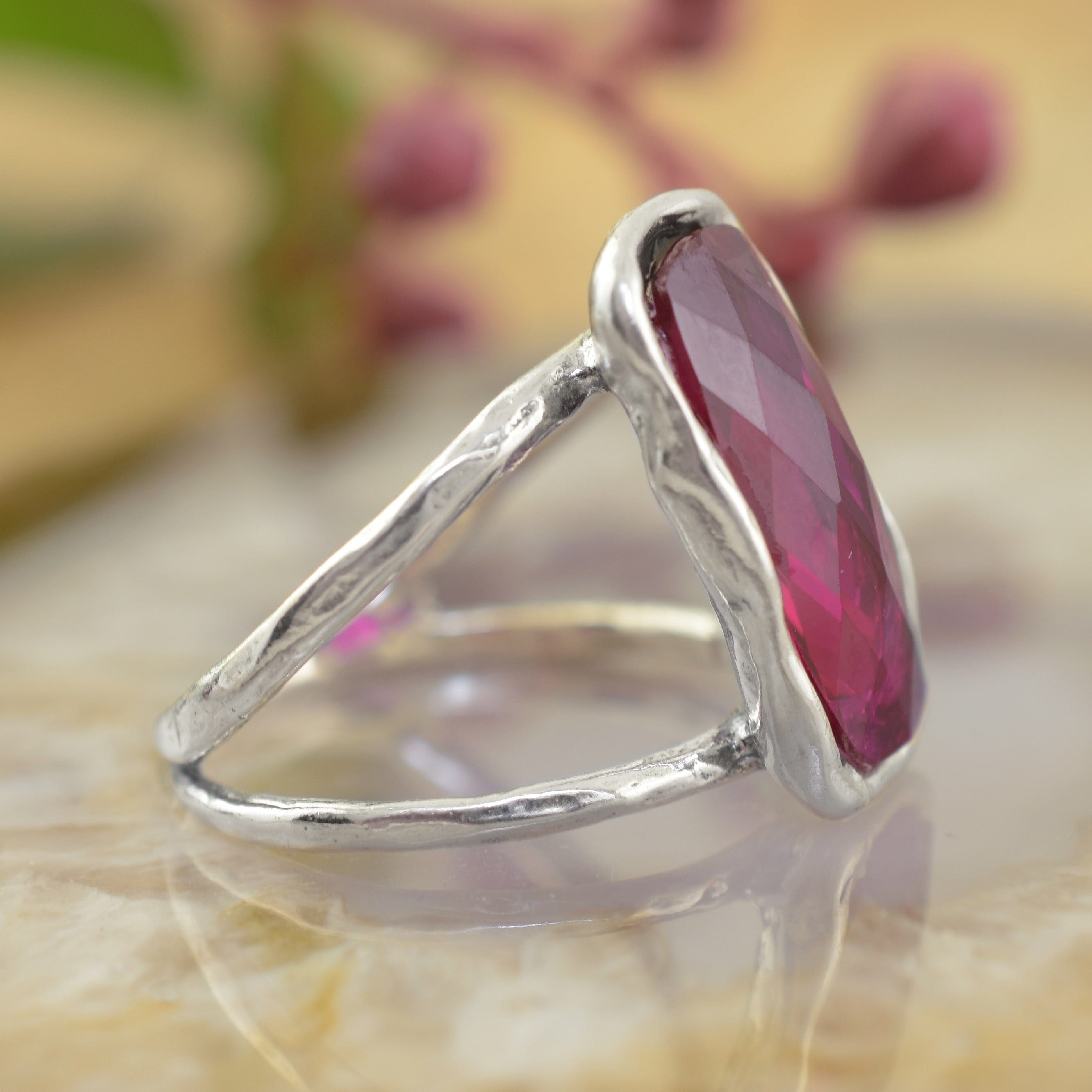 a sterling silver ring featuring a large, faceted rectangular magenta-pink gemstone sitting on an organic silver band