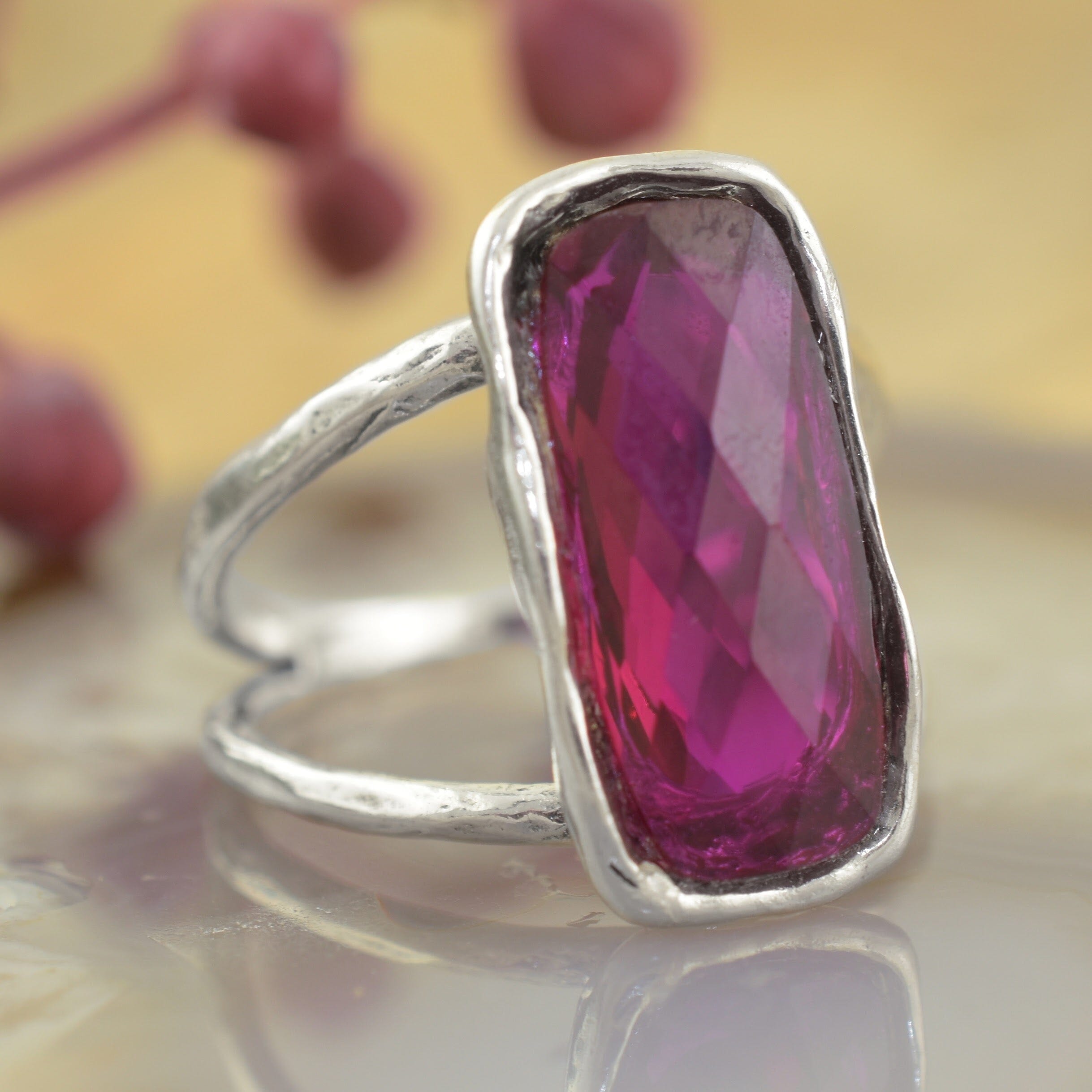 a sterling silver ring featuring a large, faceted magenta-pink rectangular gemstone