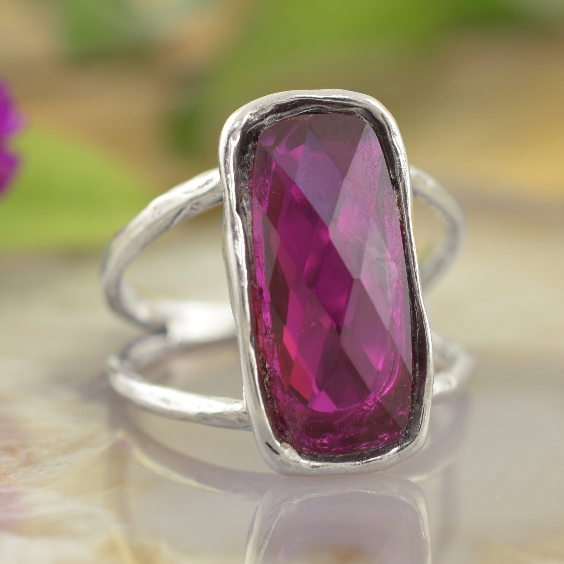 a sterling silver ring featuring a large, faceted magenta-pink rectangular gemstone