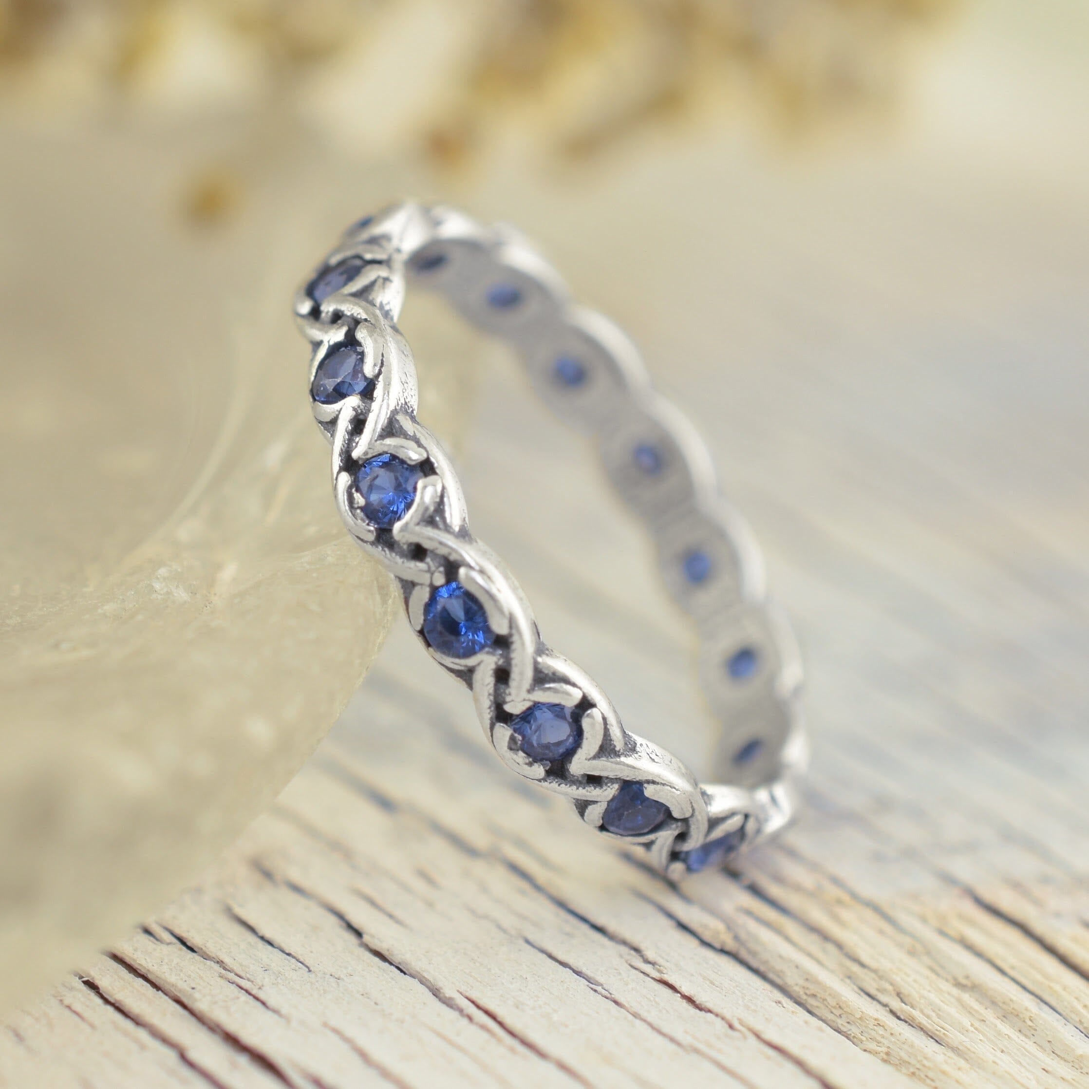 A sterling silver ring featuring a braided design around the band, set with round blue sapphires