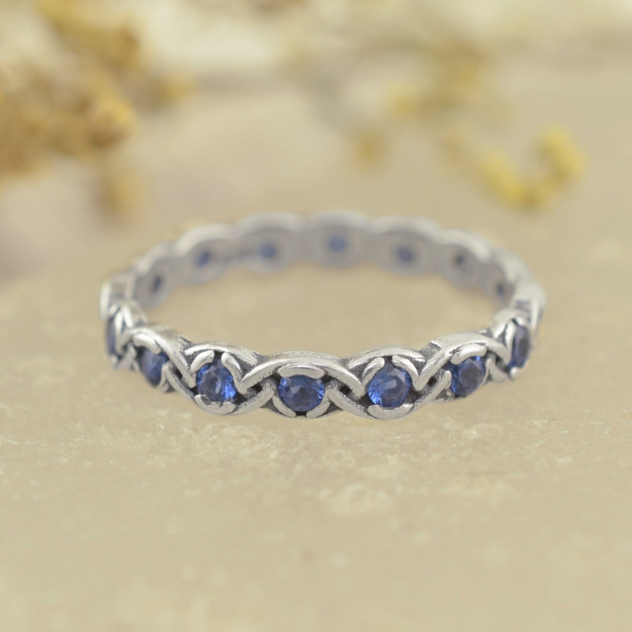 A sterling silver ring featuring round blue sapphire gemstones set in a continuous braided pattern