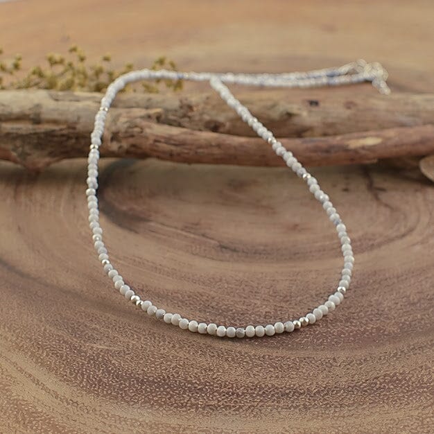 a handcrafted beaded necklace with small, faceted white and grey round beads
