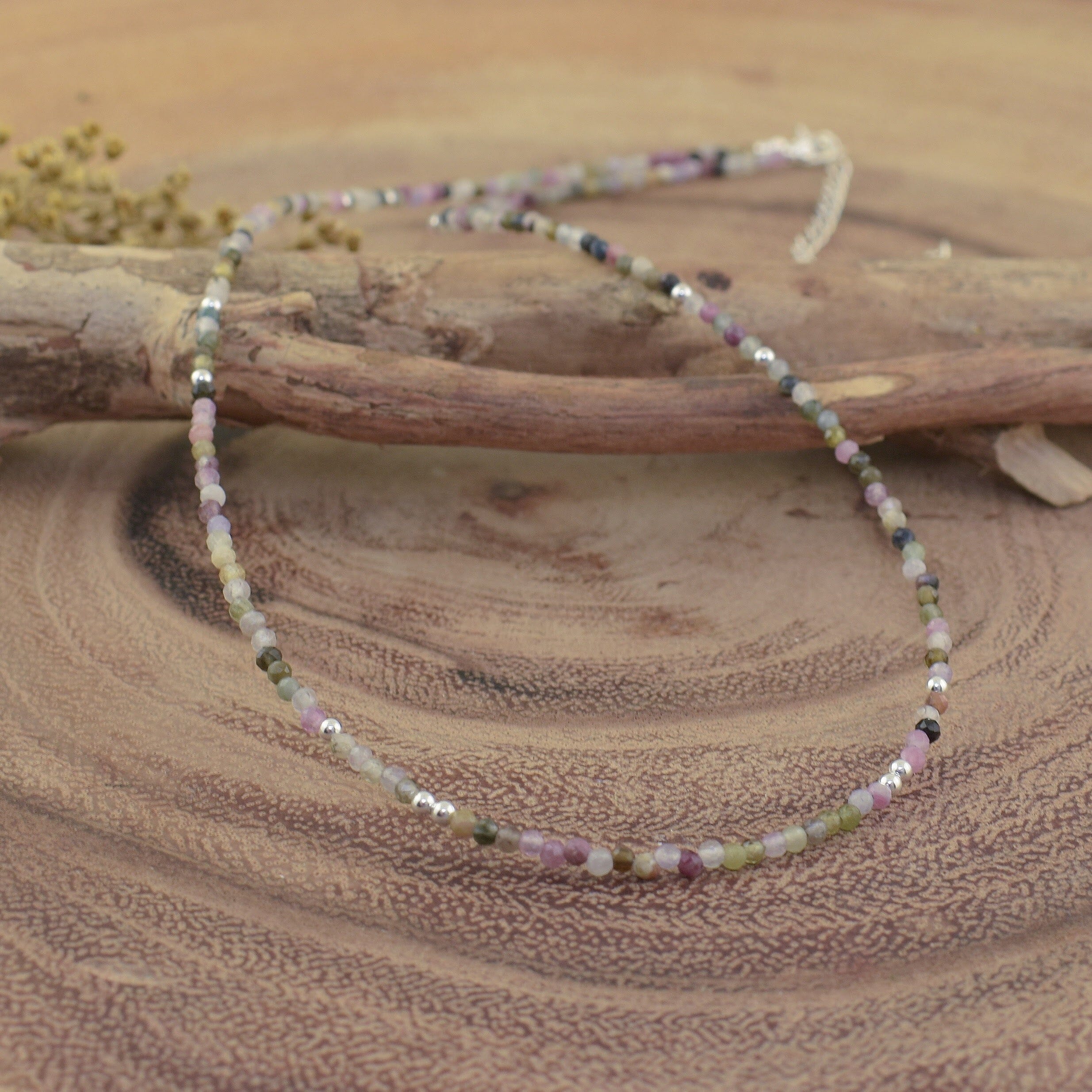 a multi-colored tourmaline beaded necklace made of small faceted gemstone beads in soft pink, green, gray, and white tones
