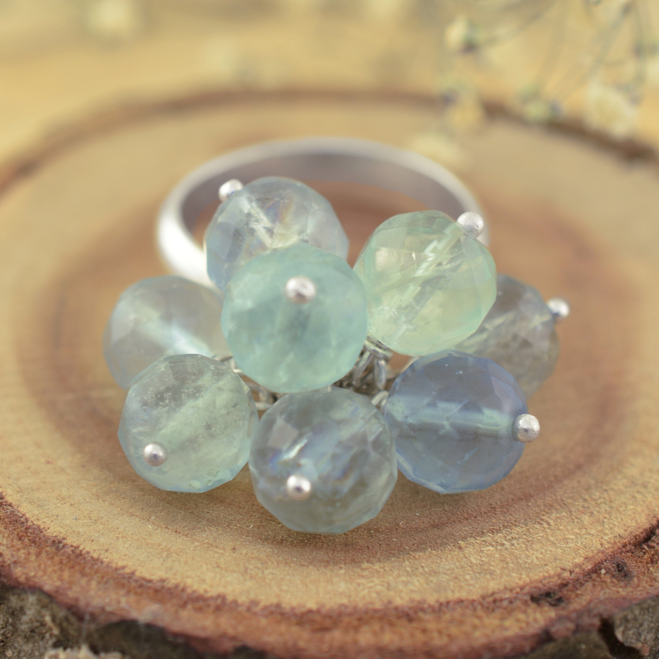 A sterling silver ring featuring a cluster of faceted light blue beads