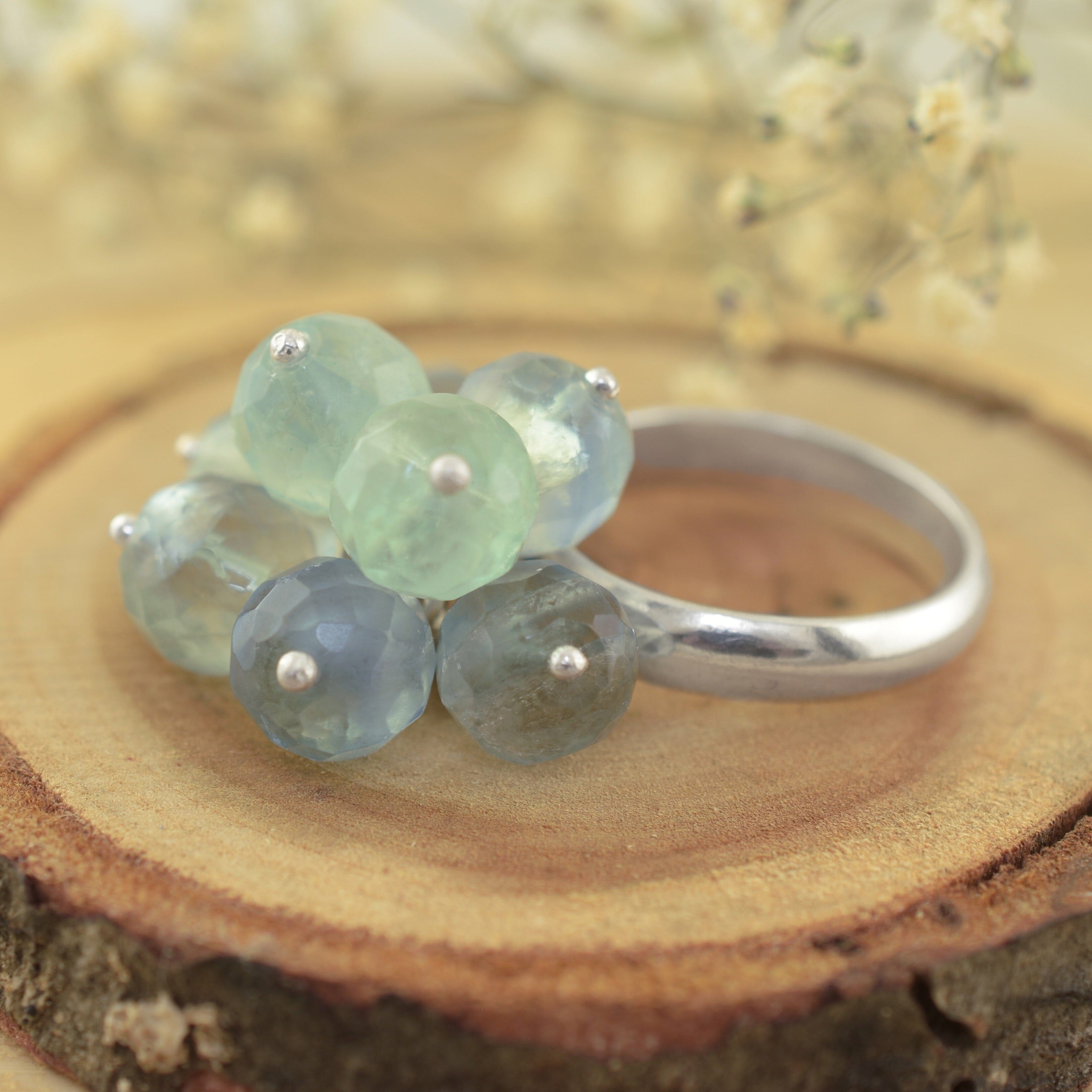 A sterling silver ring featuring a cluster of faceted light blue beads