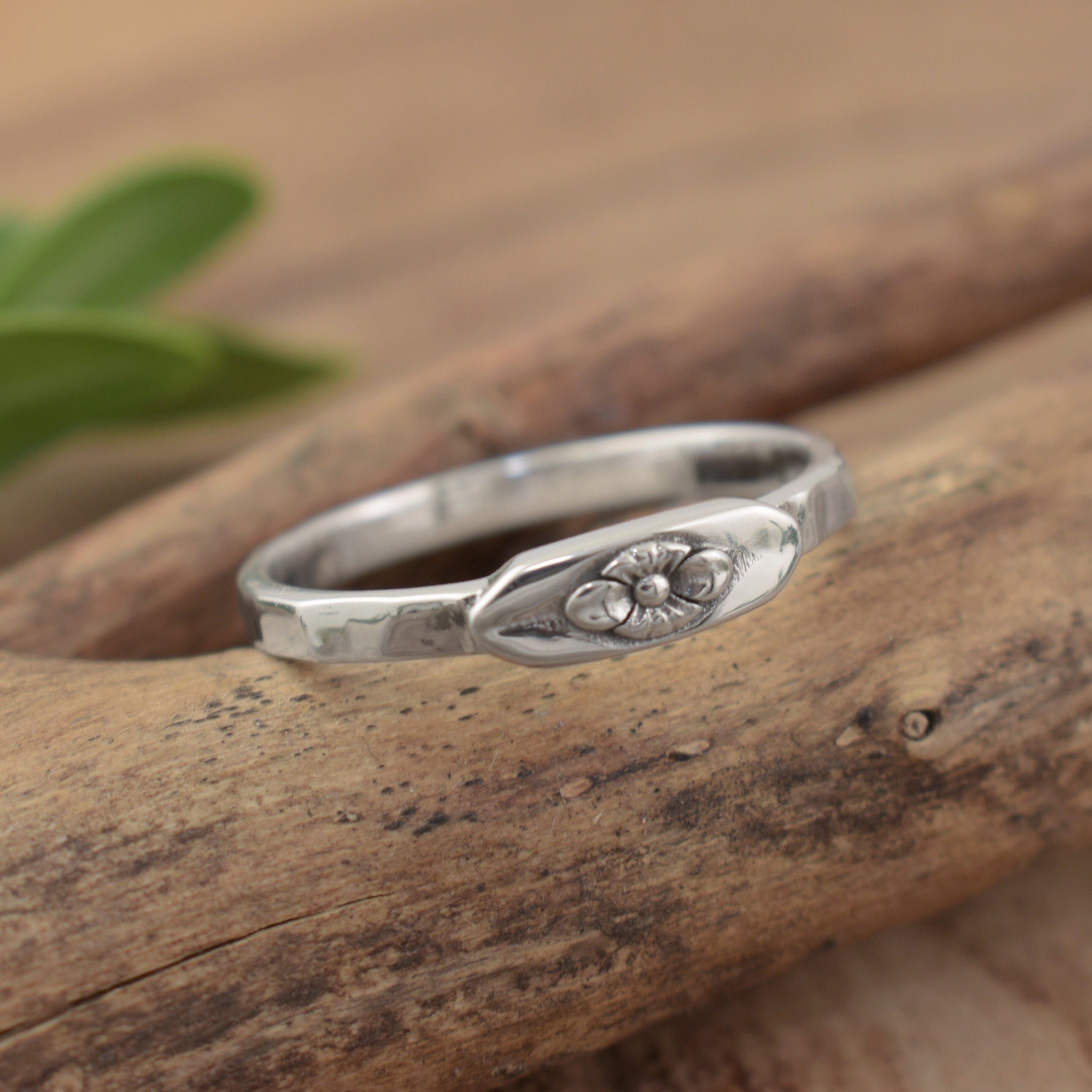 A dainty sterling silver ring with a small flower detail in the center