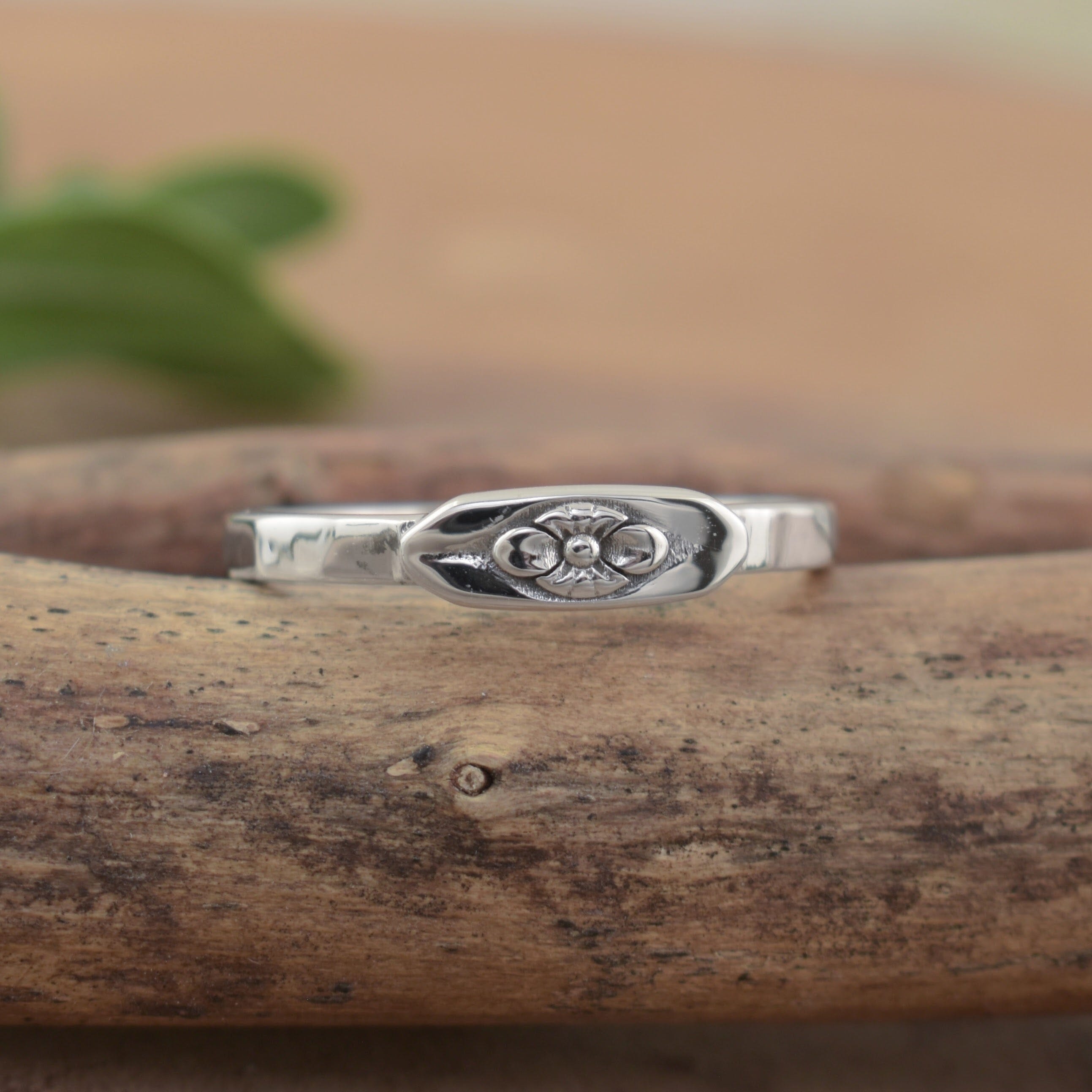 A delicate sterling silver ring with a small flower design in the center of the band