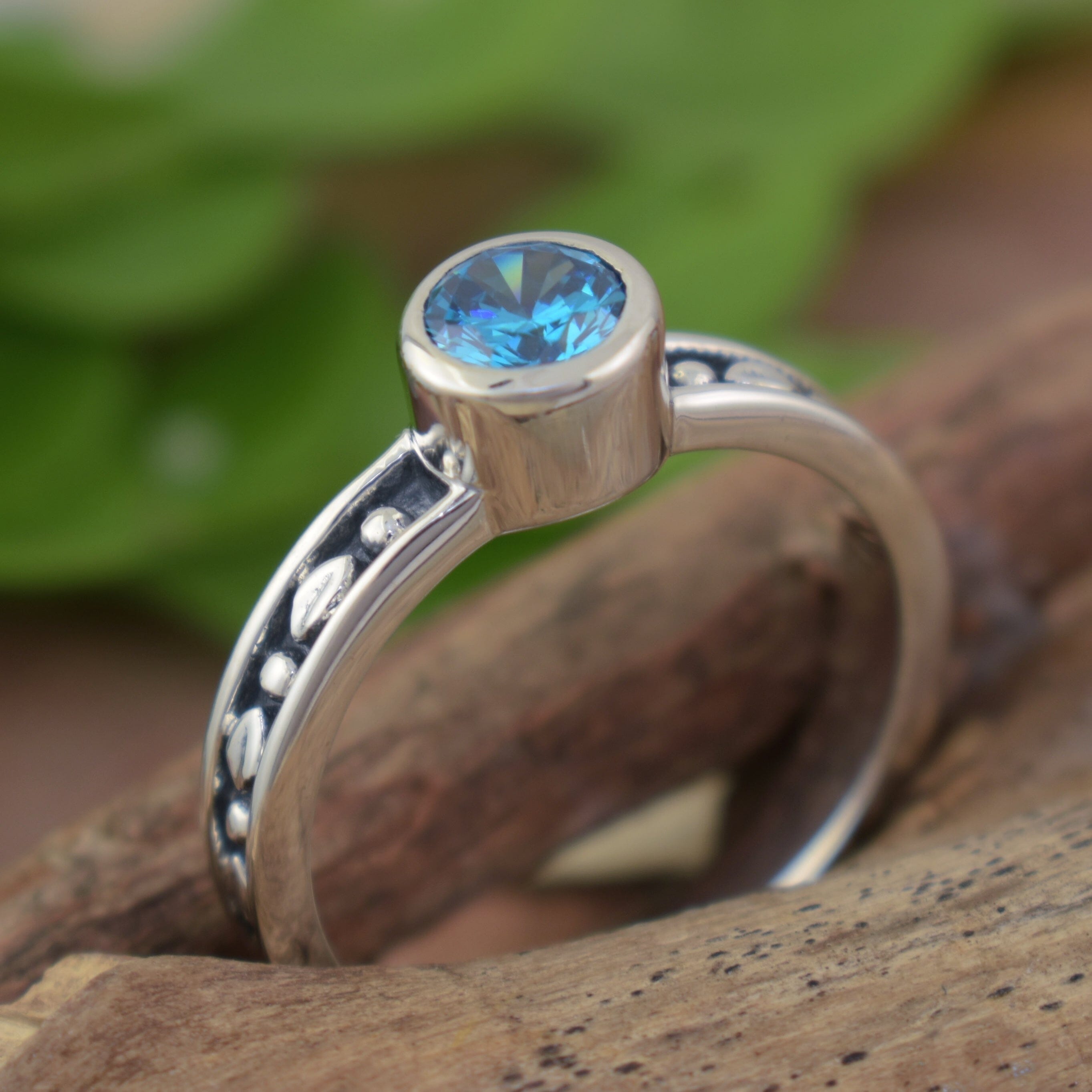 Minimalist sterling silver ring featuring round blue topaz stone