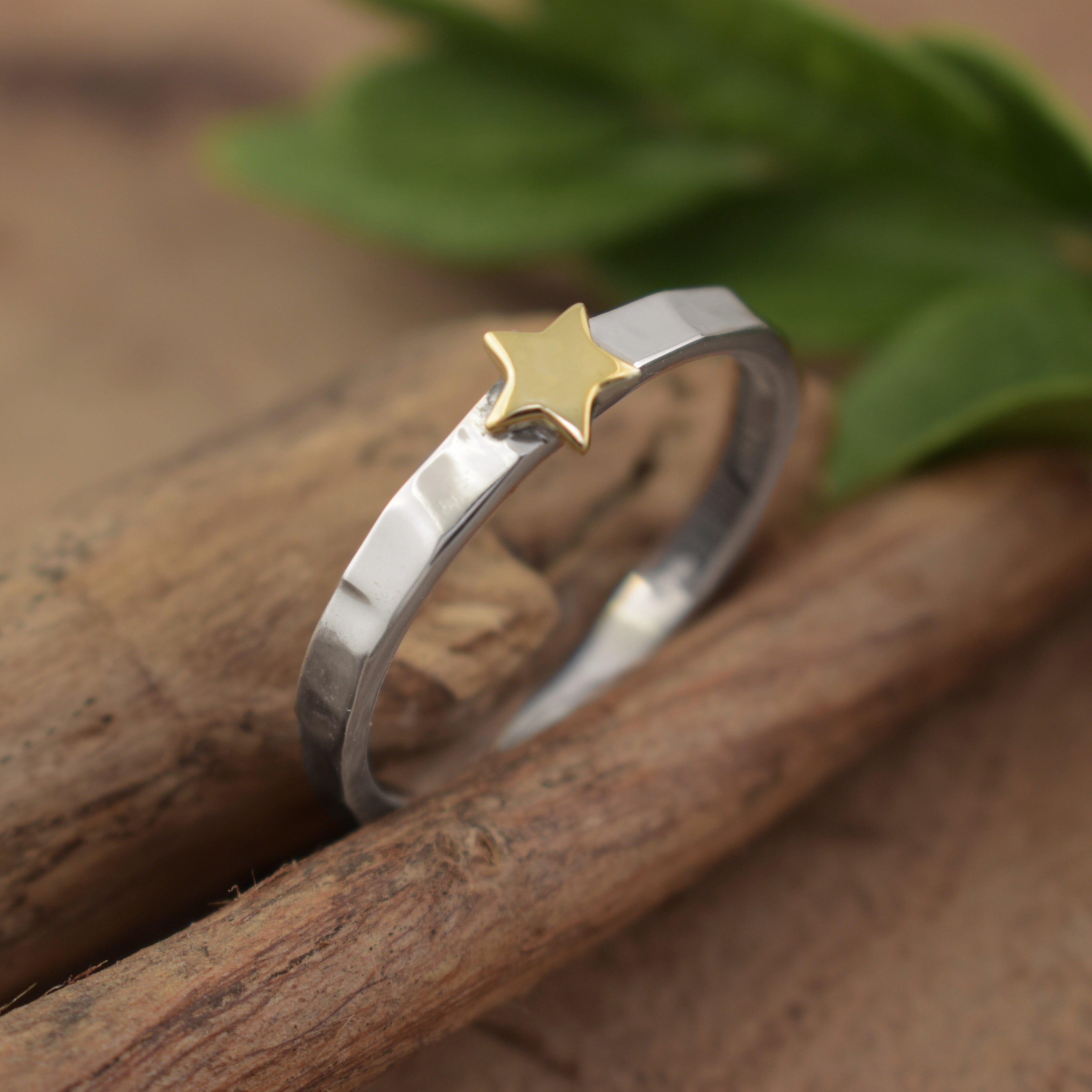 A dainty sterling silver ring featuring a small brass star in the center of the band