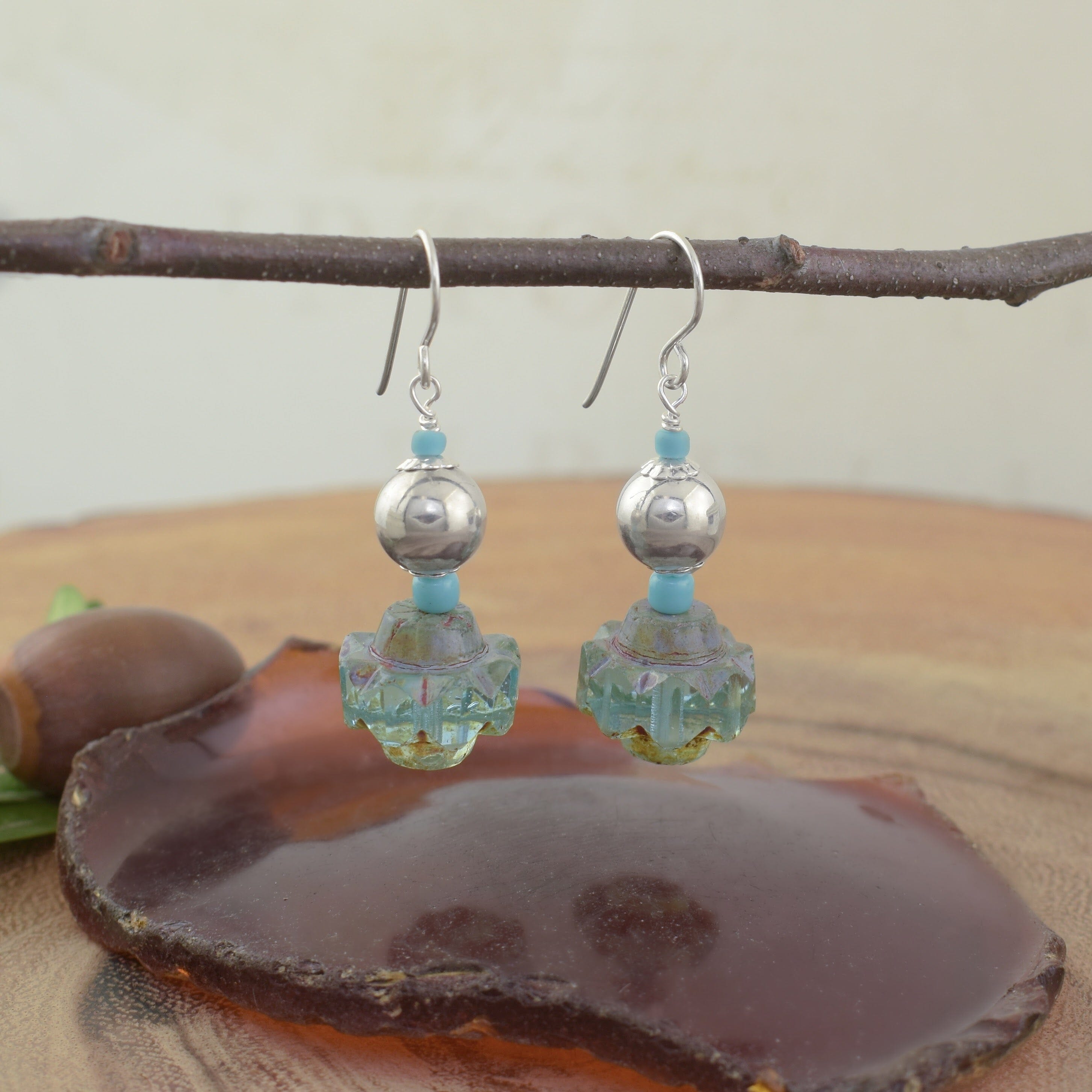 A pair of dangly earrings with a sterling silver ball and turquoise beads dangling from the hook