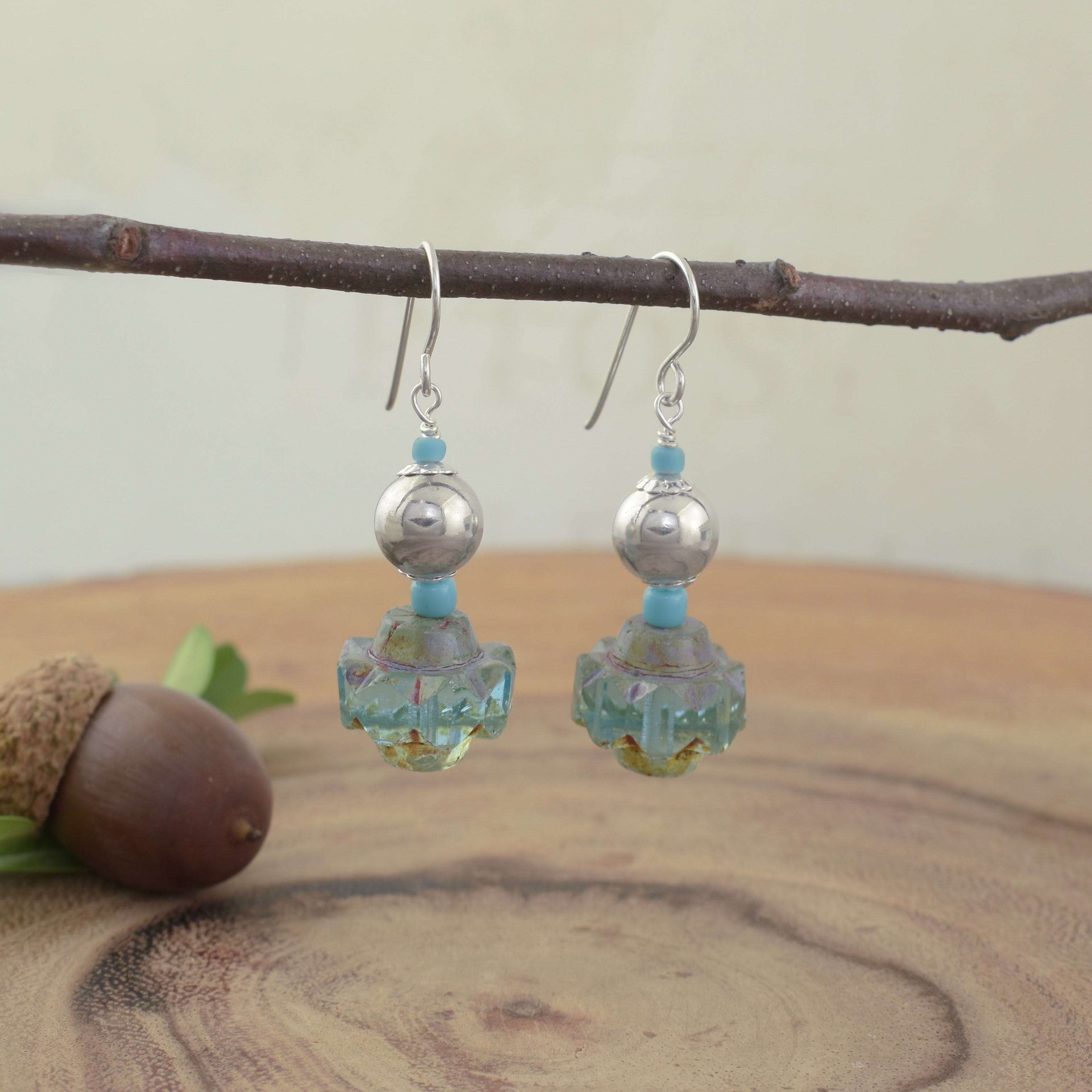 A pair of hook earrings with a sterling silver bead and turquoise beads dangling from the hook