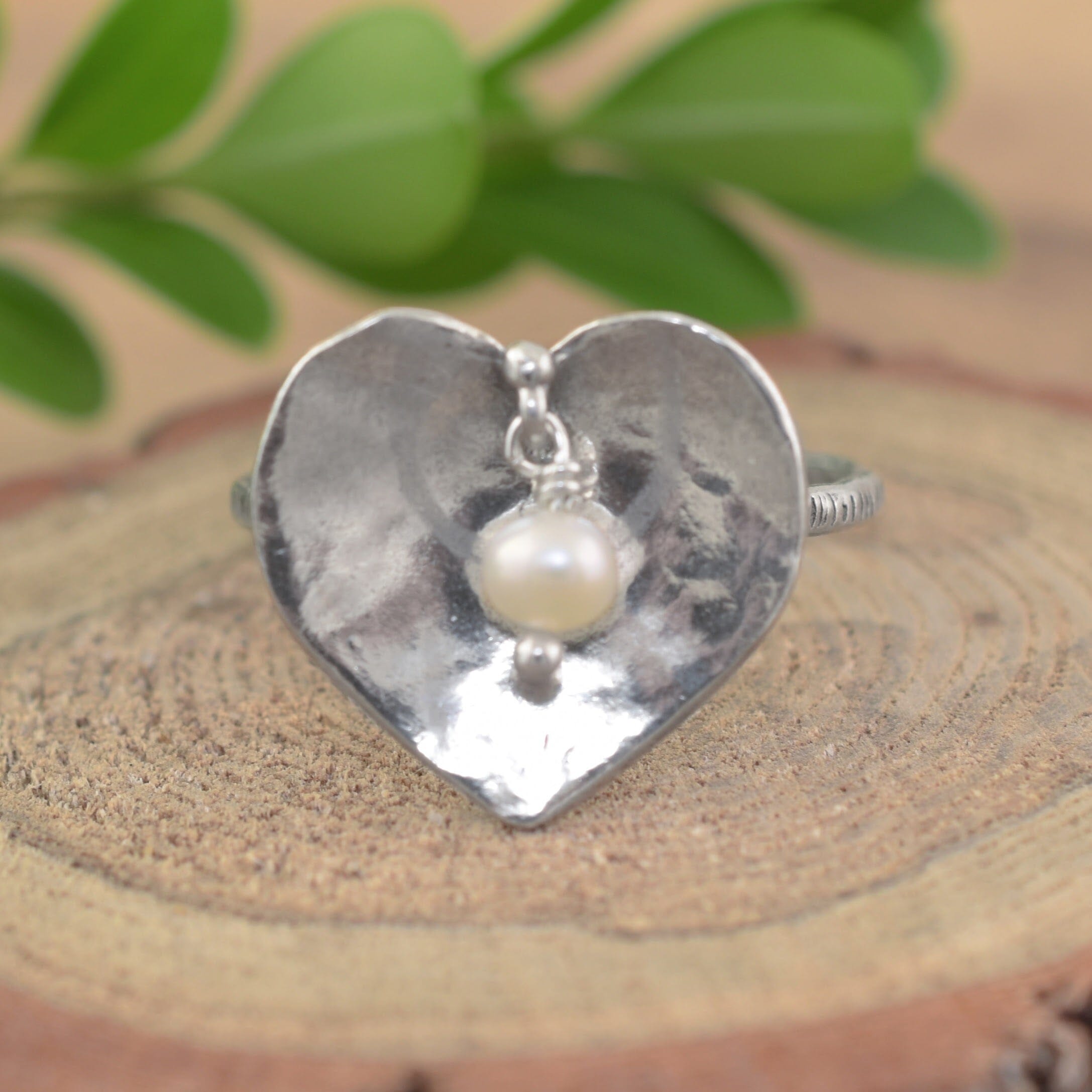 A sterling silver heart-shaped ring with a dangling white pearl