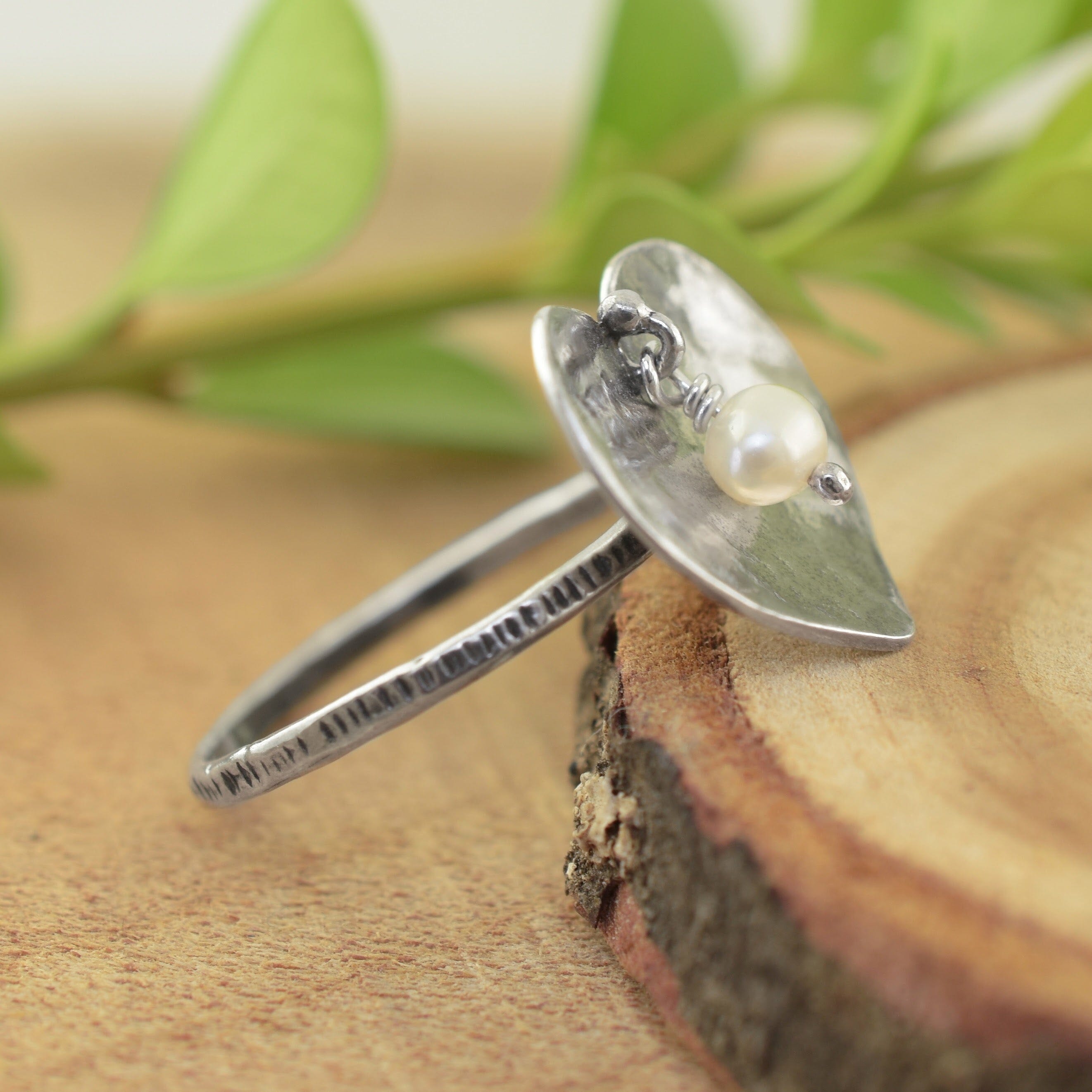 A sterling silver ring with a hammered heart-shaped top and a small white pearl
