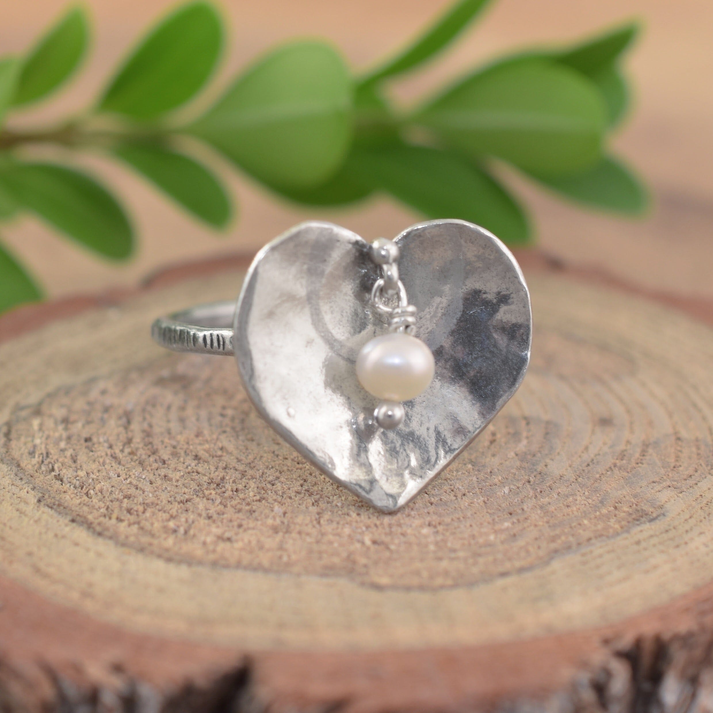 A sterling silver heart-shaped ring with a small white pearl at the center
