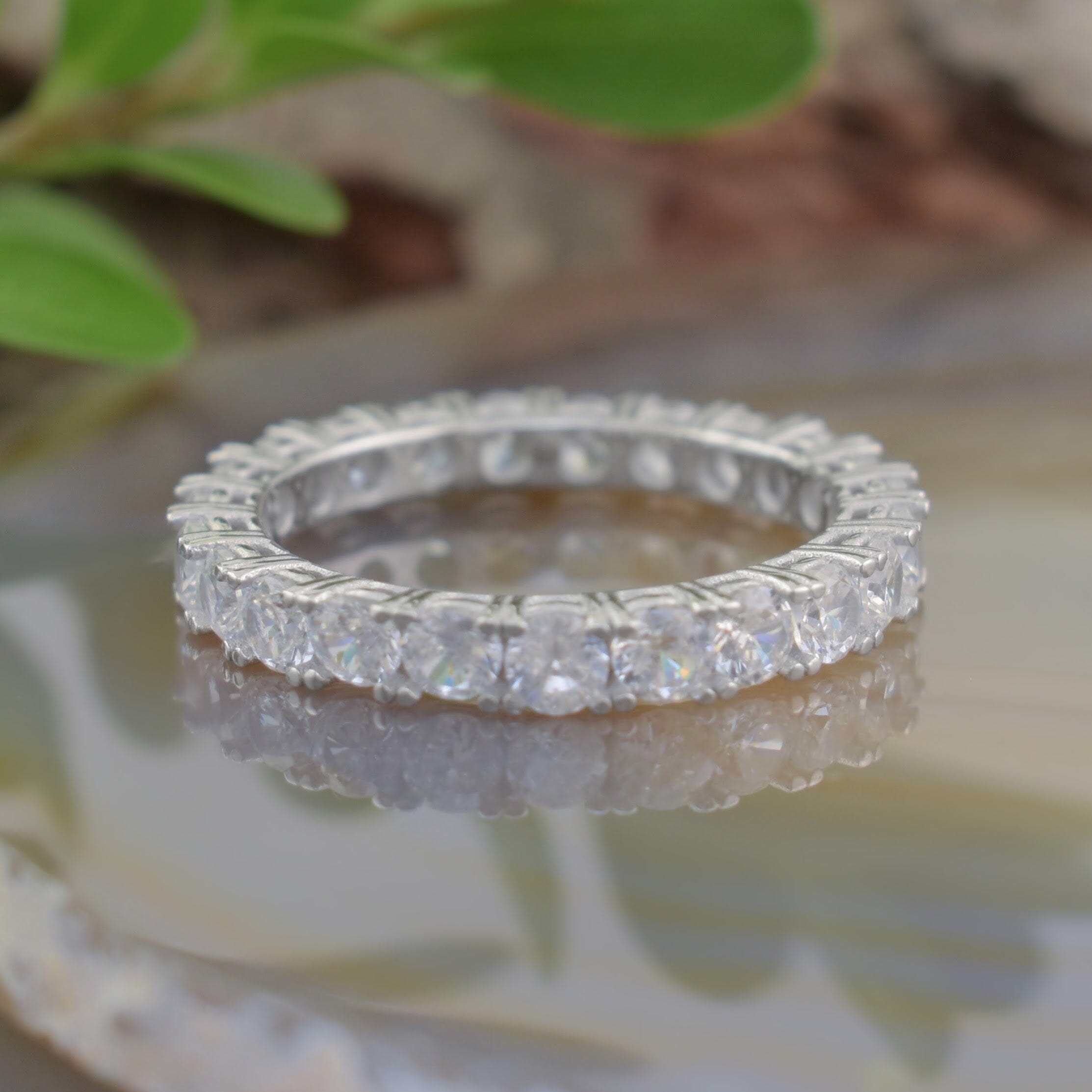 A silver ring with small Zircon stones surrounding the outside of the band