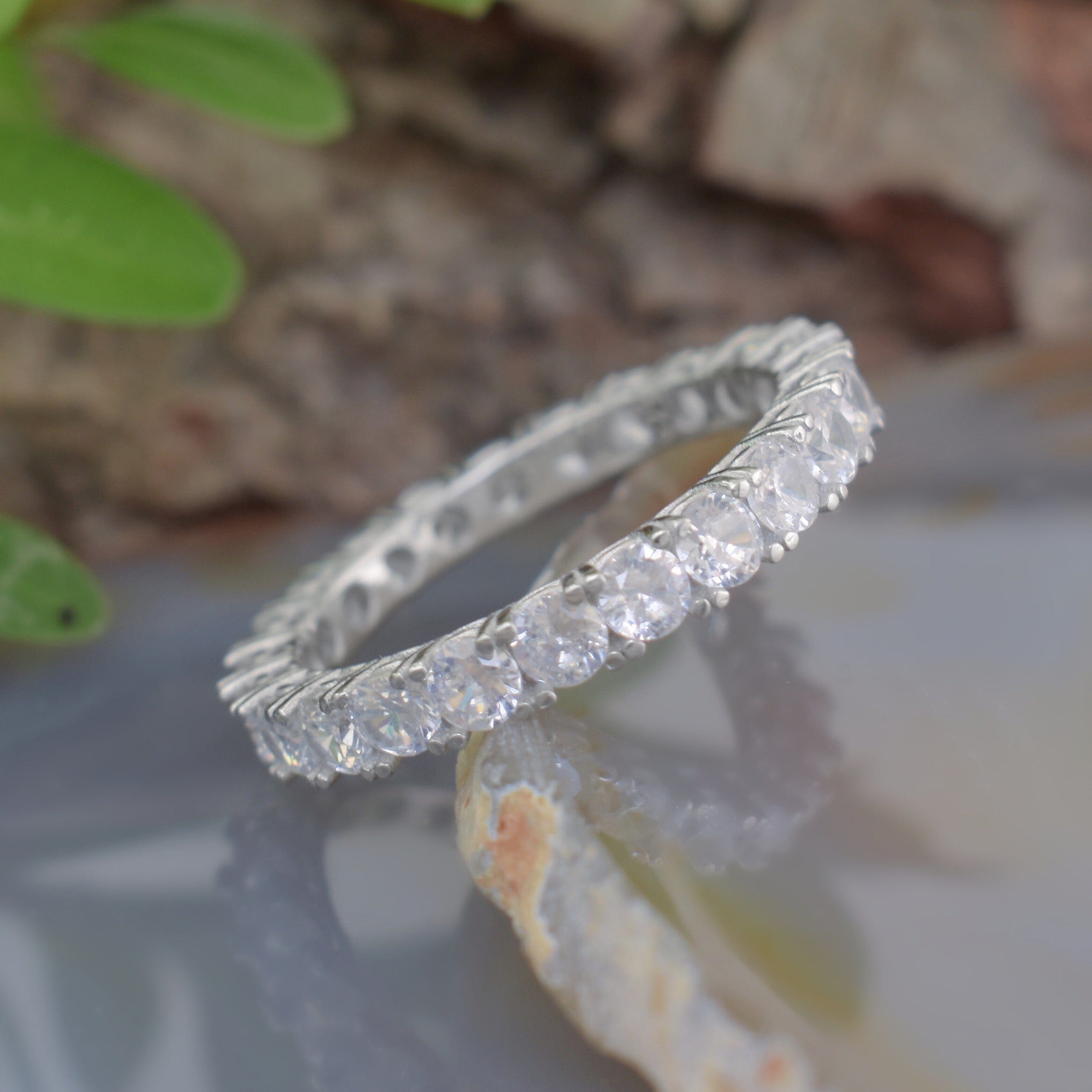 A silver ring with small Zircon stones surrounding the outside of the band
