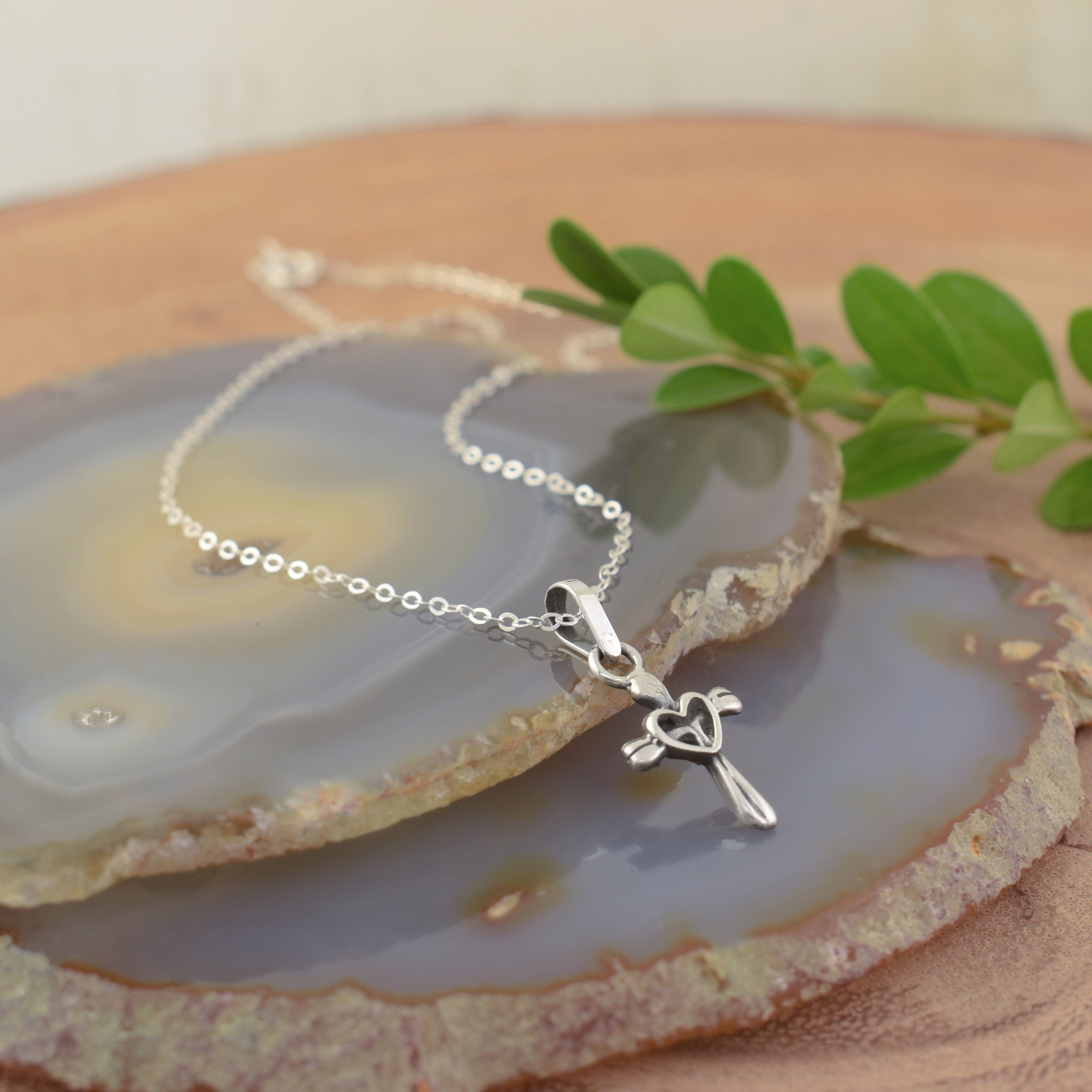 A sterling silver necklace featuring a cross pendant with an open heart in the center