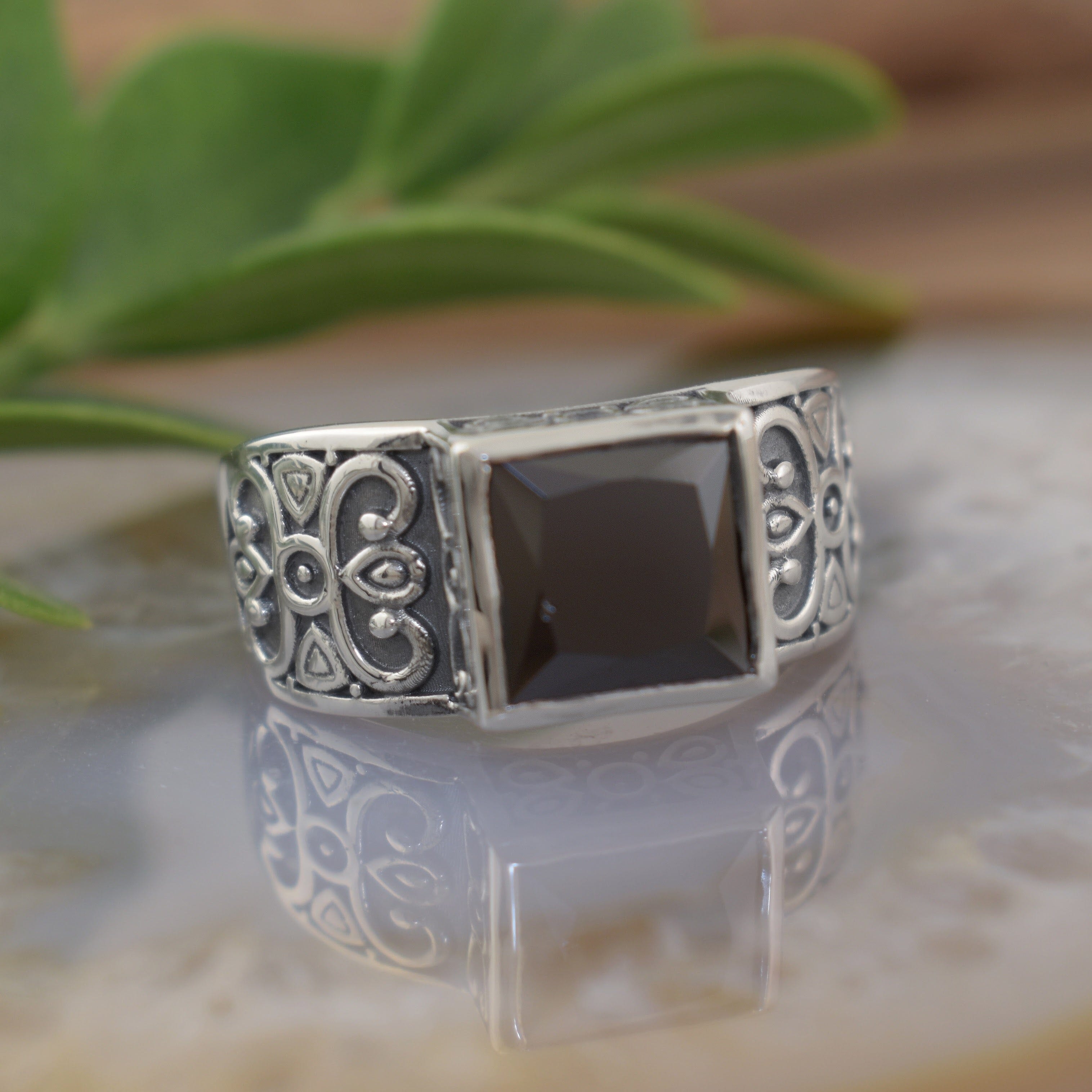 A sterling silver ring with scrollwork along the band, featuring a large square black CZ stone