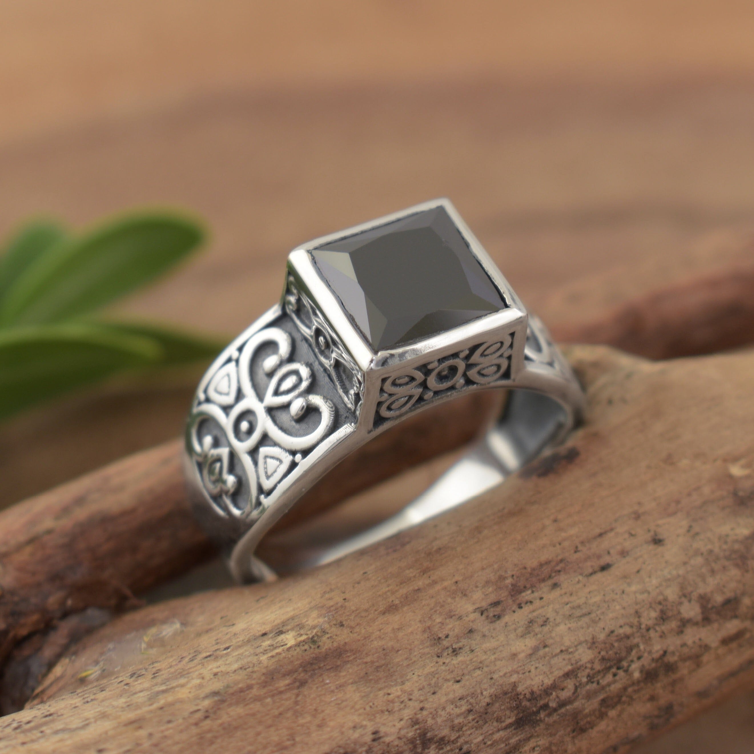A sterling silver ring featuring engraved scrollwork along the band, with a large black square CZ stone in the center