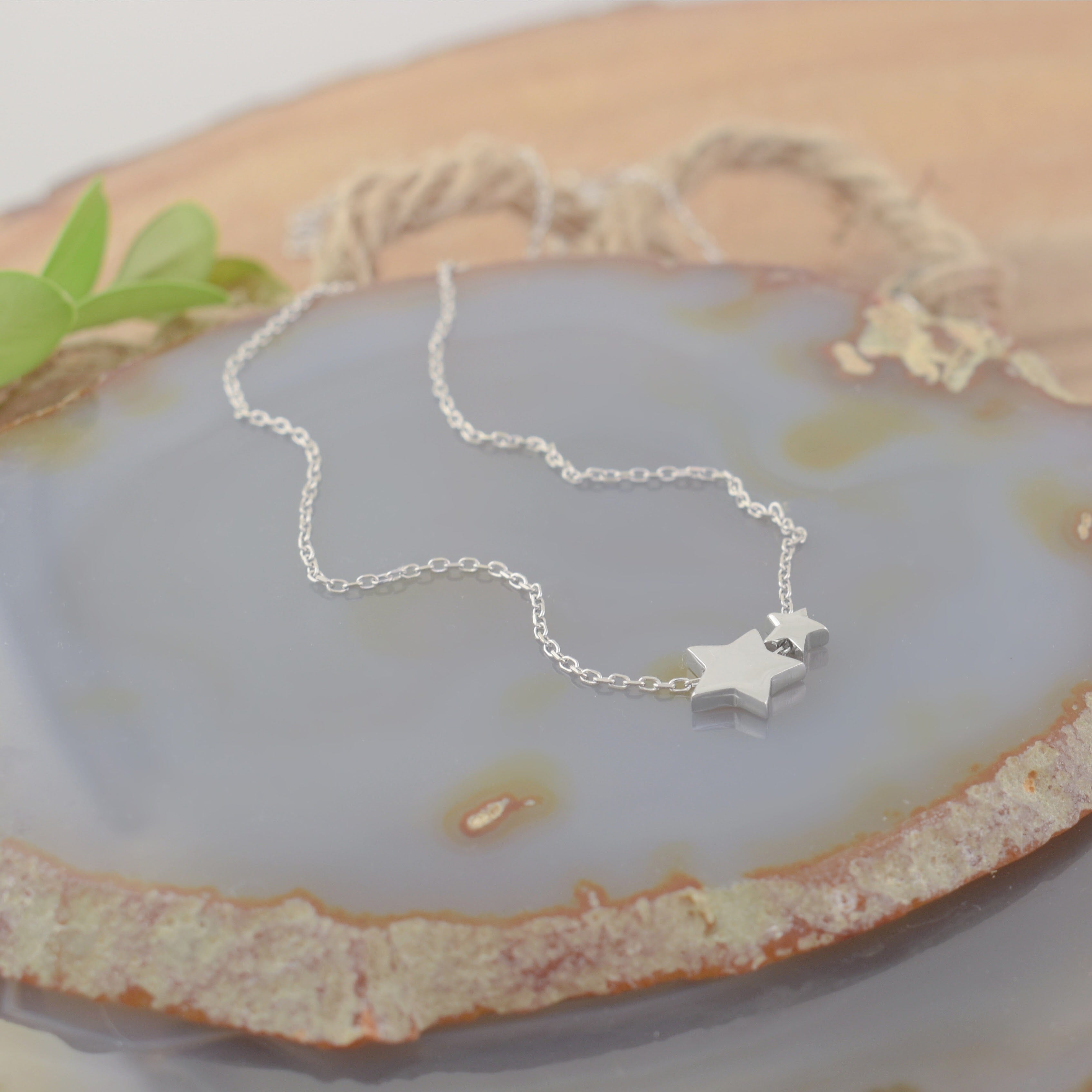 A delicate sterling silver chain necklace with two small star pendants