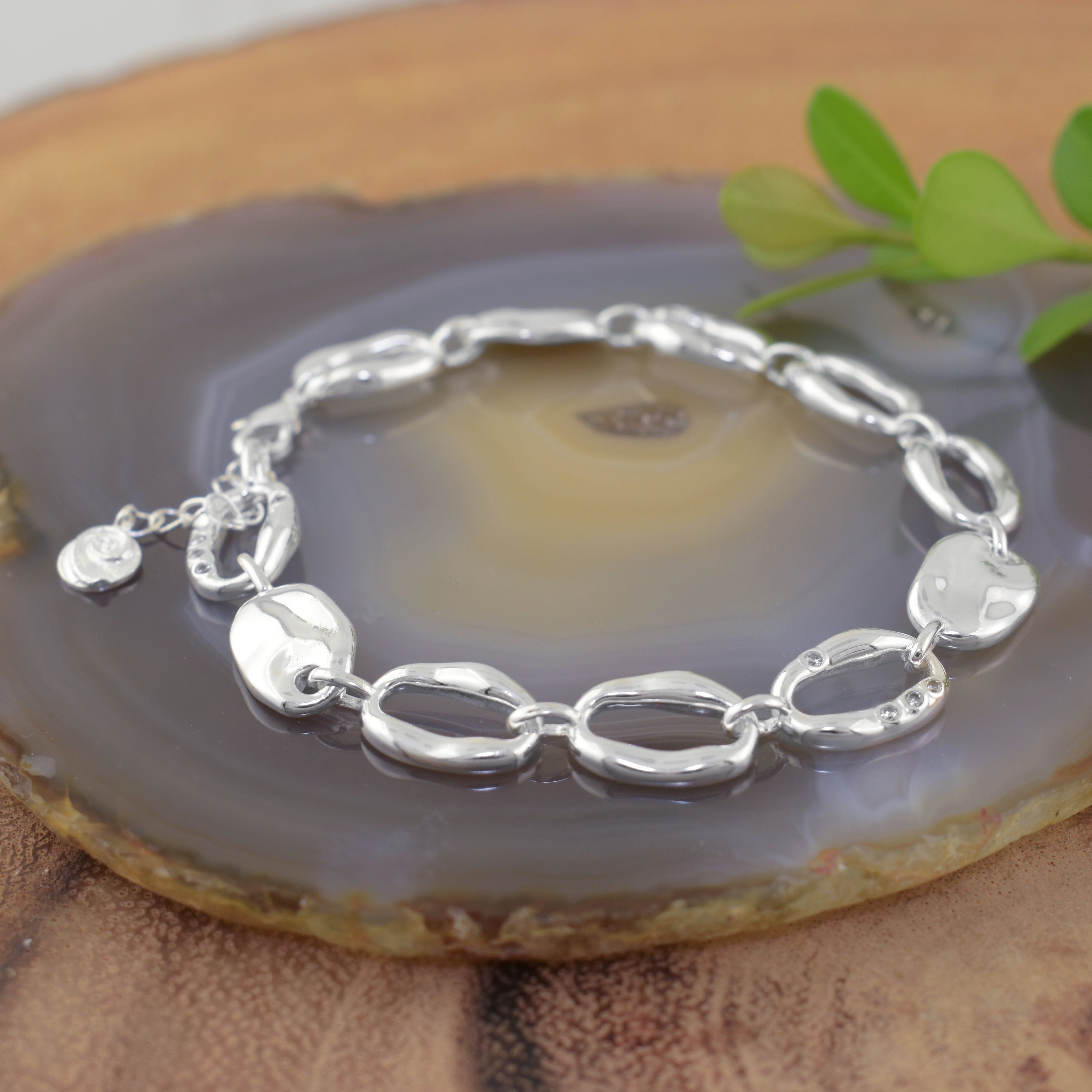 a polished sterling silver link bracelet with organic-shaped oval links and tiny CZ stones scattered on the chain links