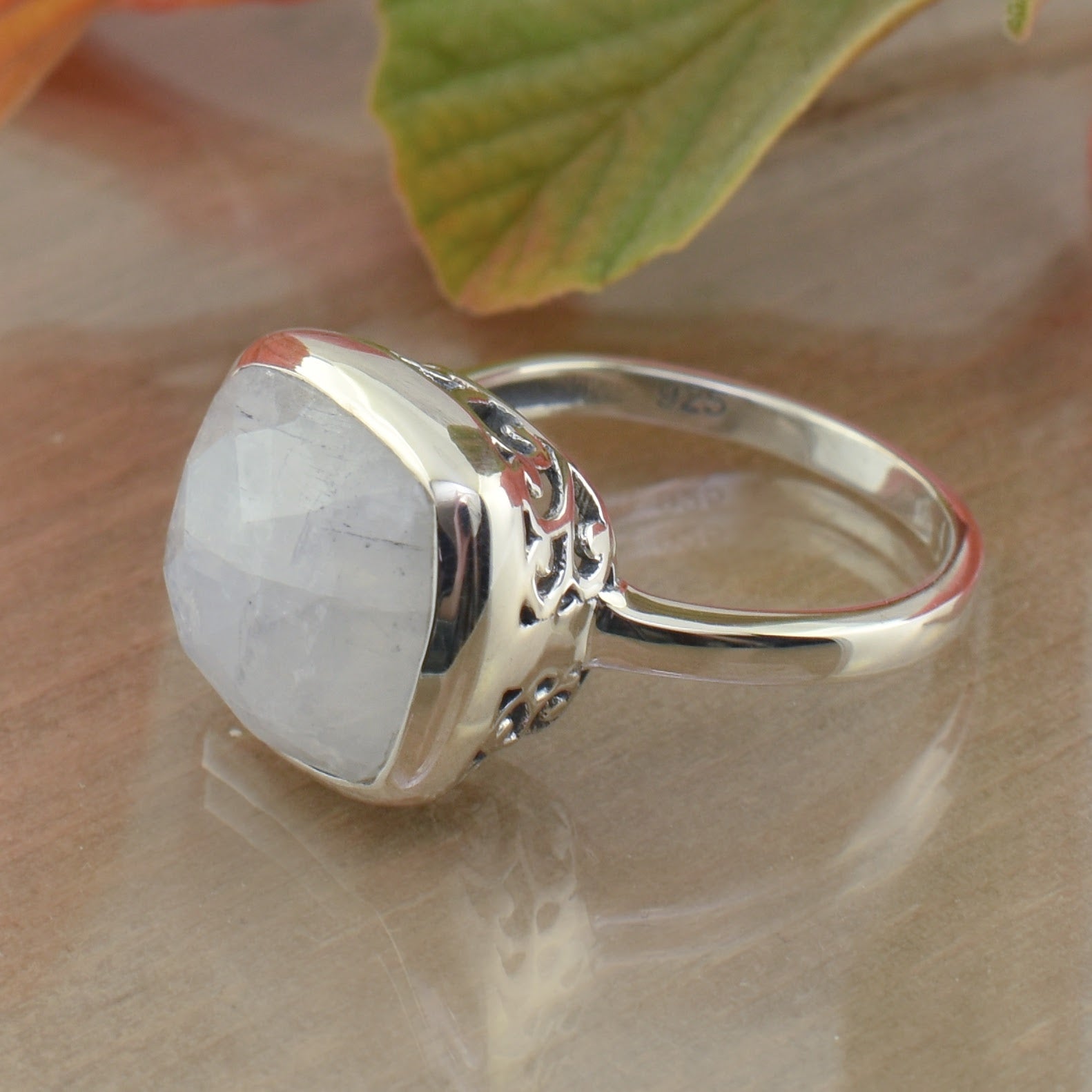 rainbow moonstone ring with thin band and bezel with cut out swirls