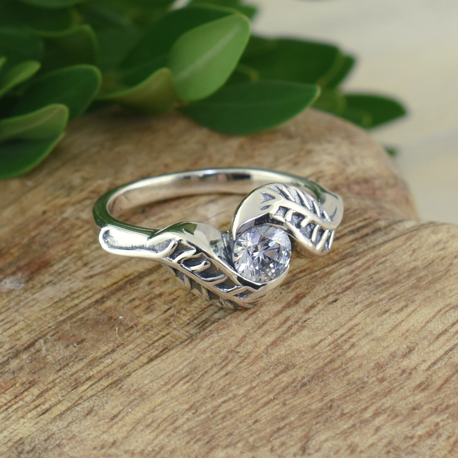 .925 sterling silver ring with a leaf on each side of a cz 