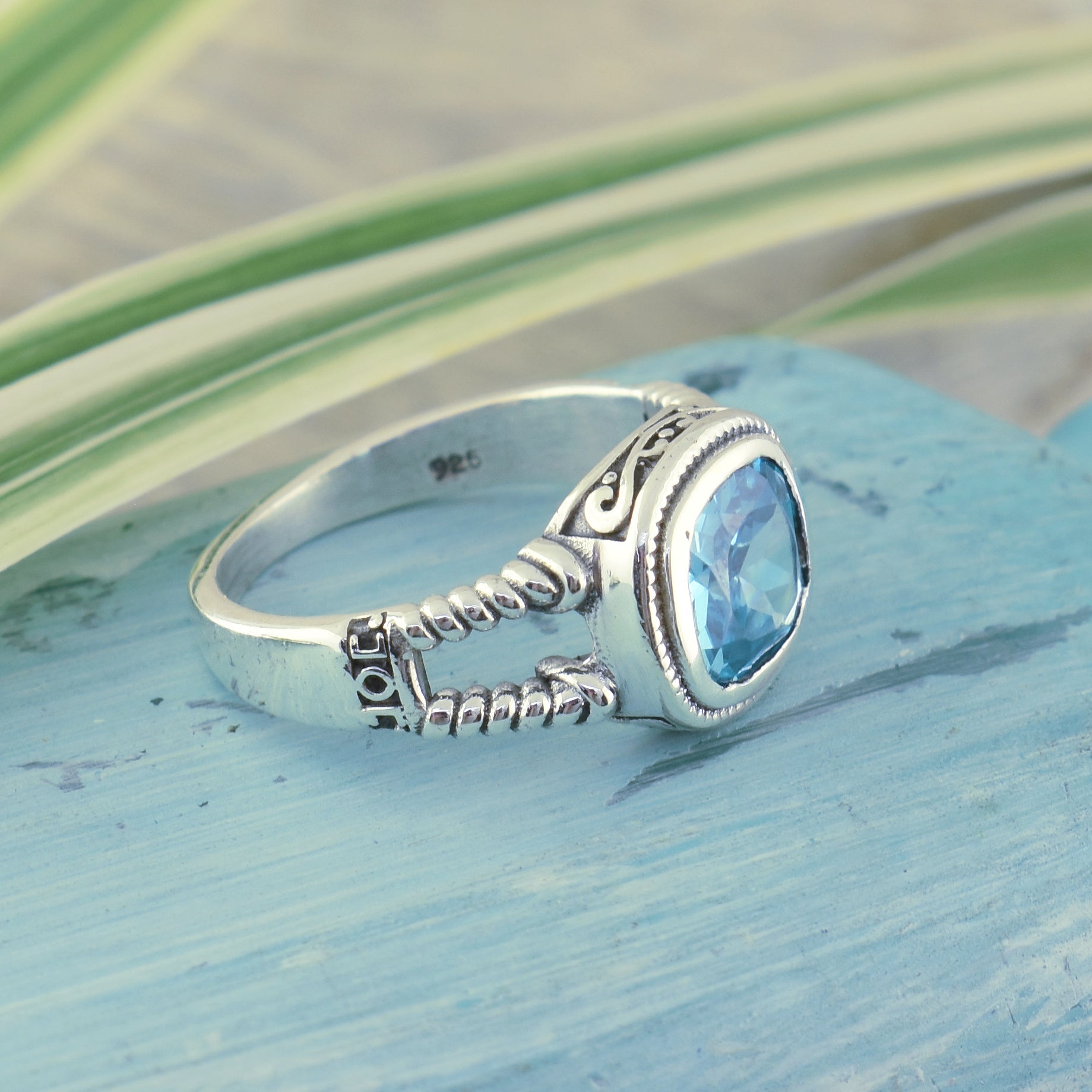 sterling silver ring with filigree and rope design and a blue topaz stone